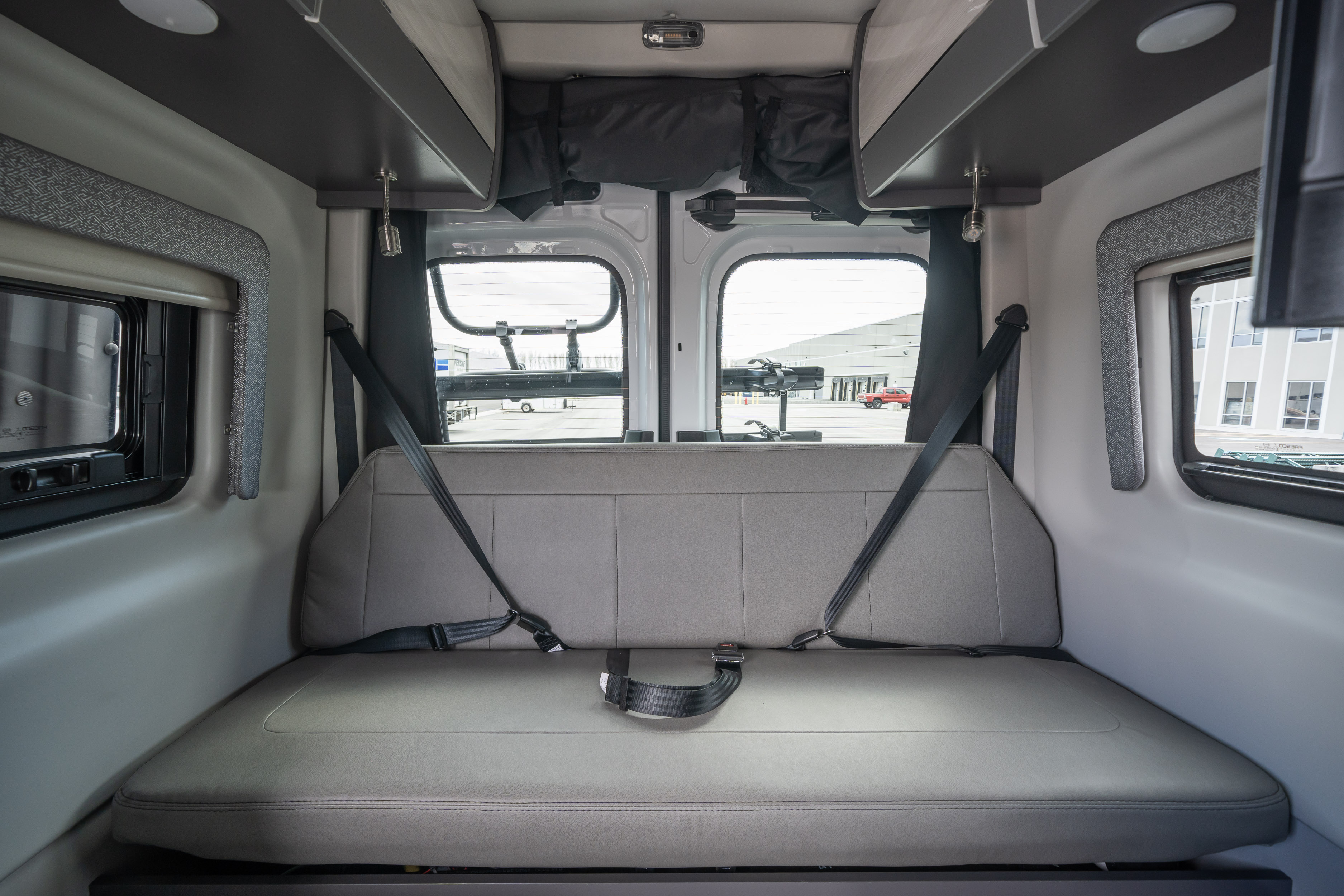 Modern RV rental interior, showing rear lounge/bed conversion with windows and overhead storage.. Thor Motor Coach Tranquility 4x4 2023