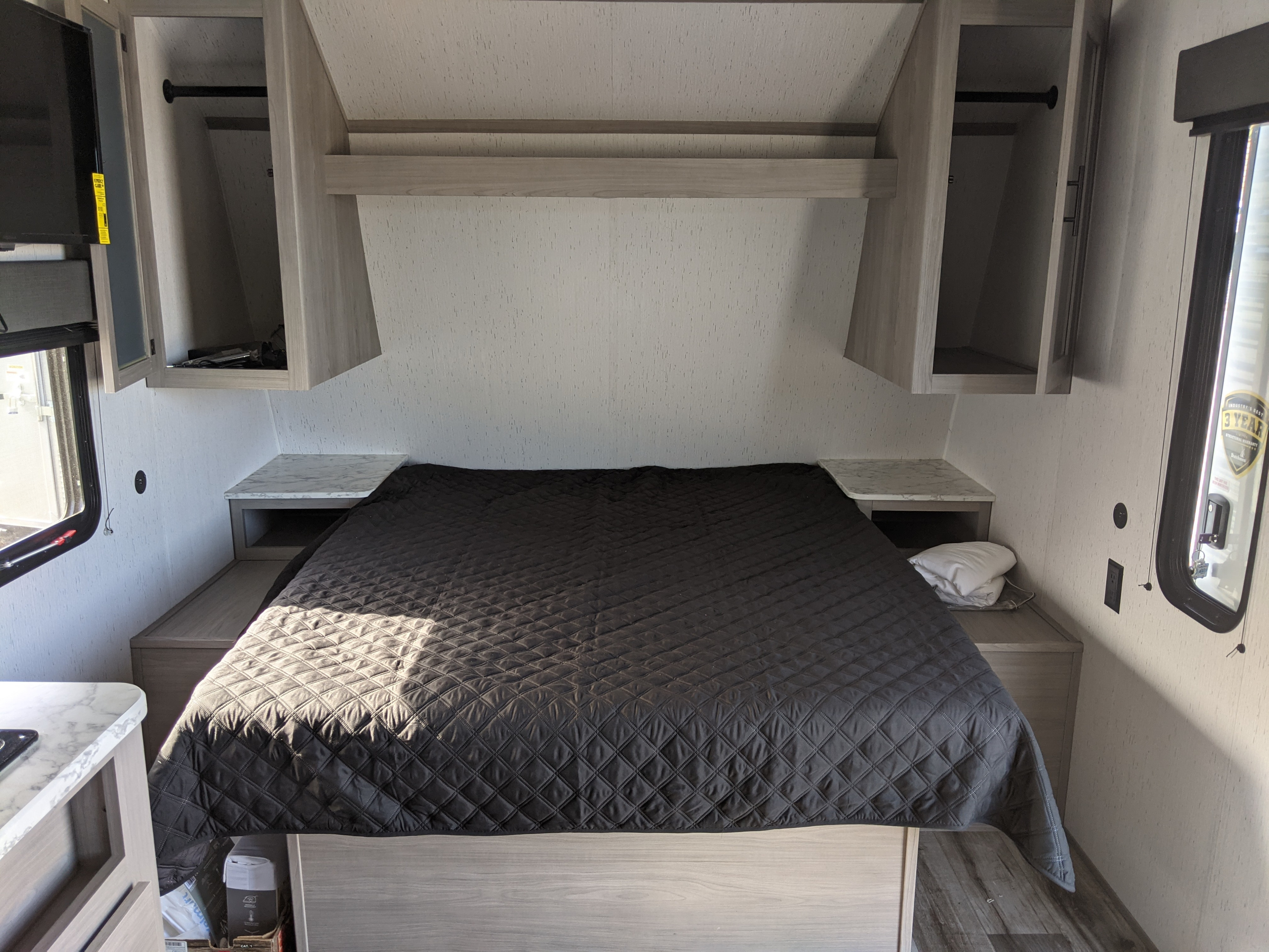 Compact RV rental bedroom with queen bed, overhead storage, and integrated nightstands.. Keystone RV Coleman 214BH 2022