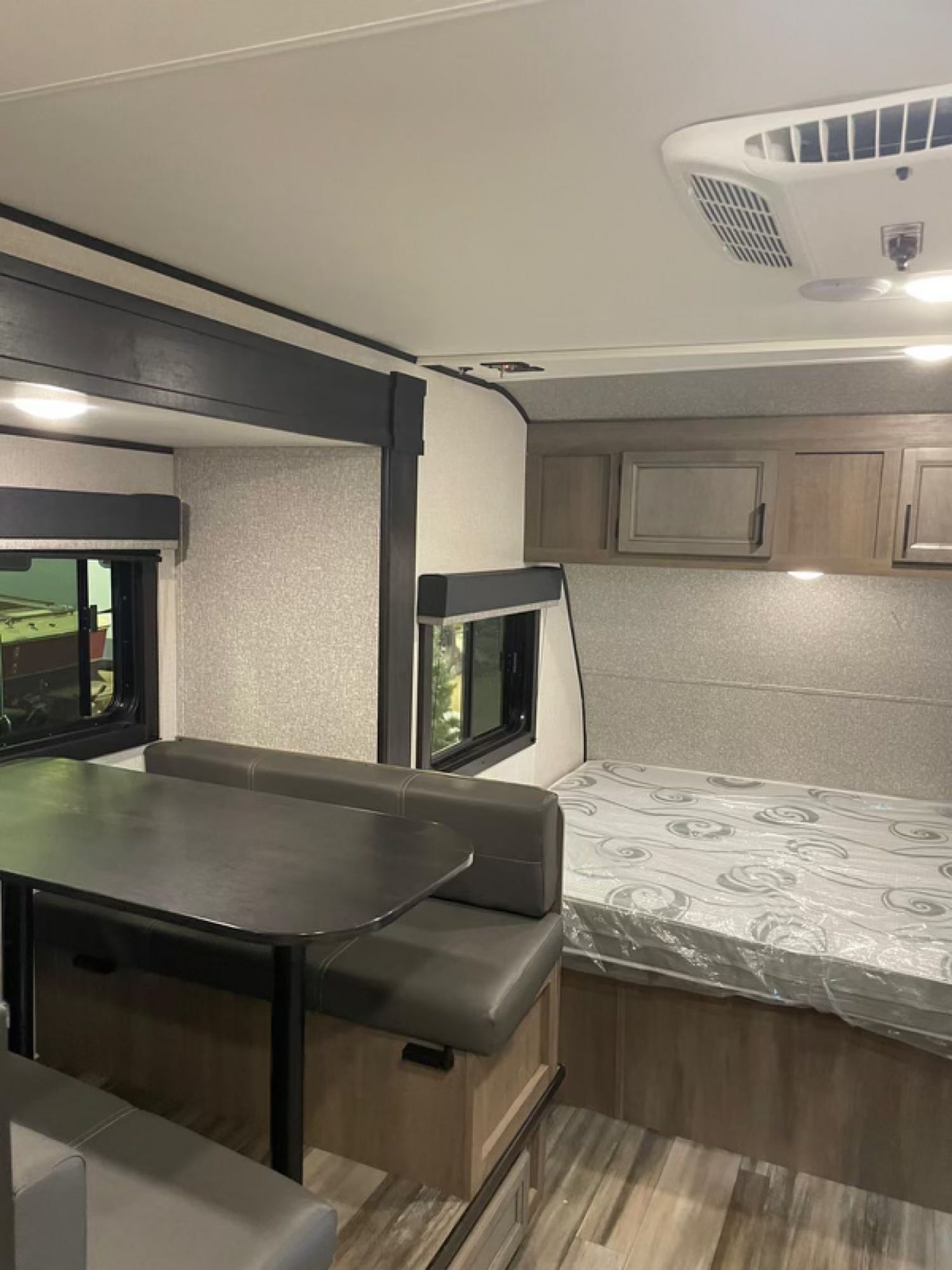 Explore this RV rental interior: cozy dinette, fresh bed with overhead cabinets, and bright living area.. Highland Ridge RV Open Range 2022