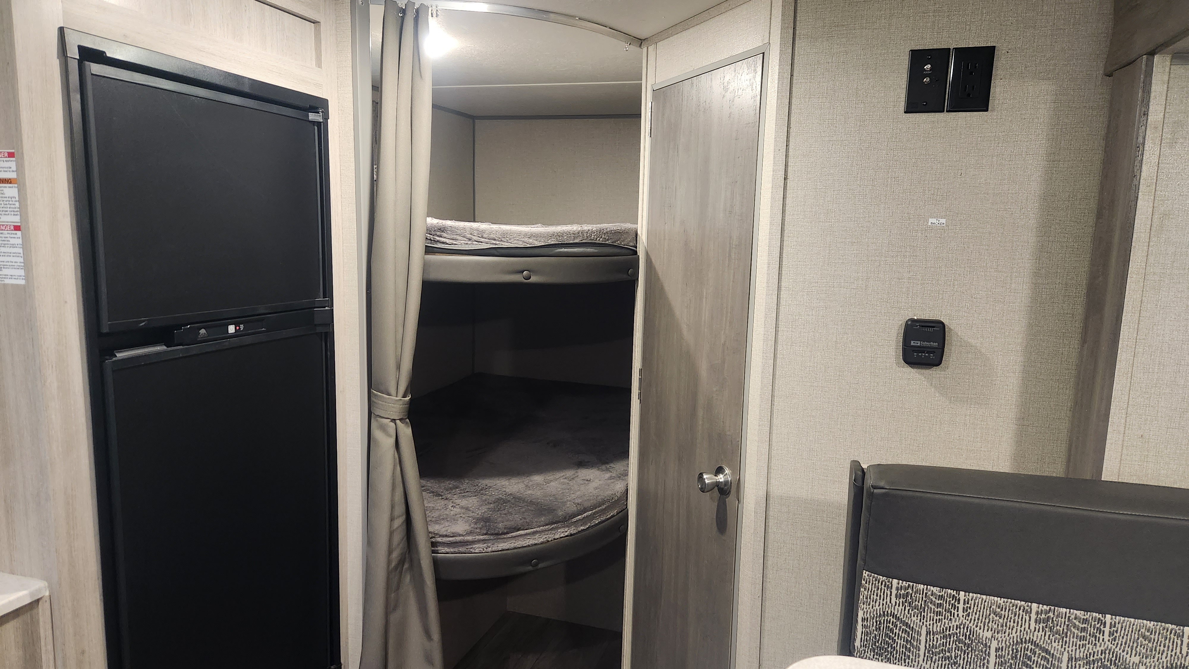 Explore this RV rental's interior: functional refrigerator, curtained bunk beds, and a cozy living area.. Coachmen Catalina Summit 2022