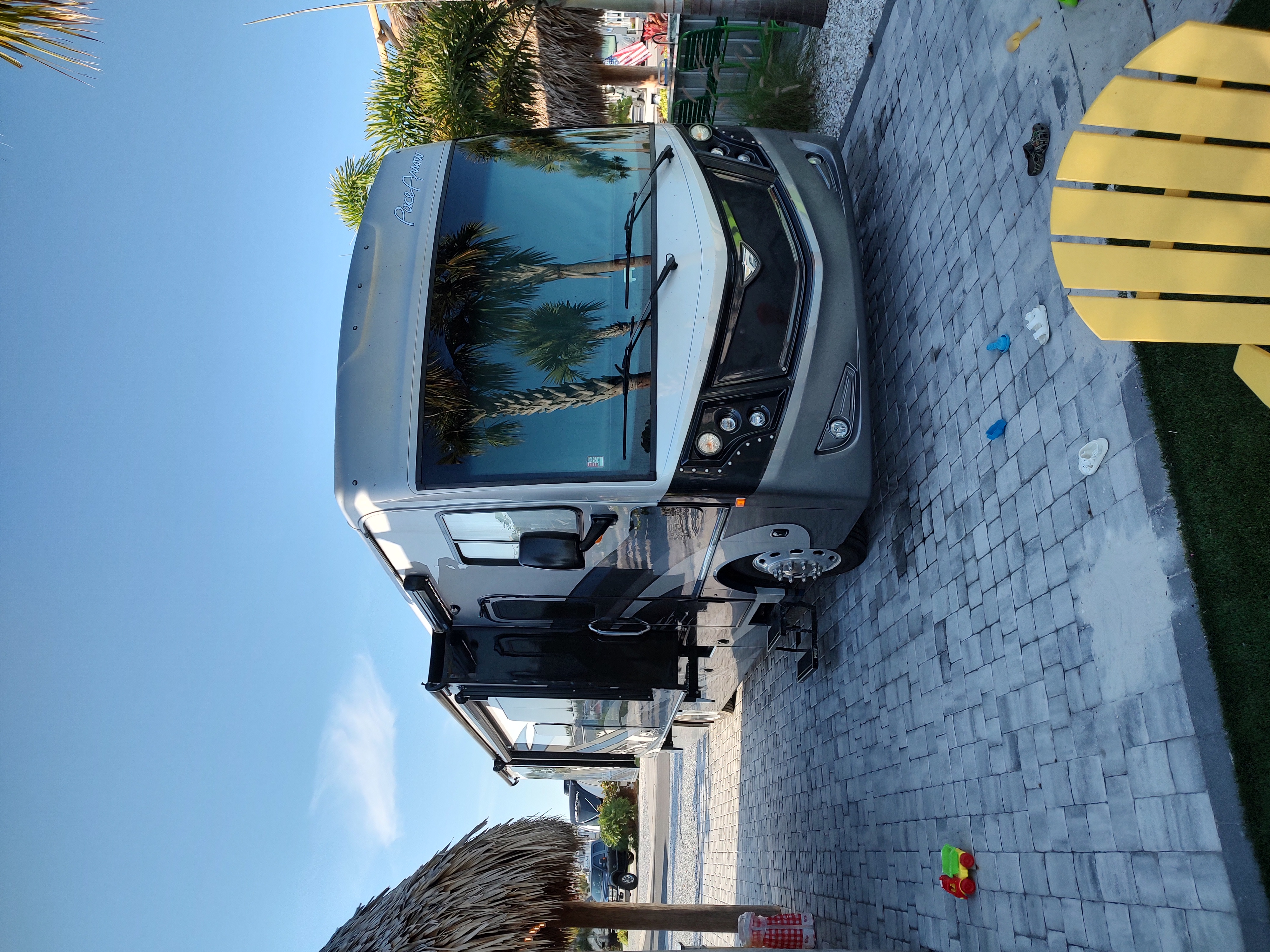 Spacious RV rental parked at a sunny resort with palm trees and a paved patio, perfect for a family getaway.. Fleetwood Pace Arrow 35QS 2021