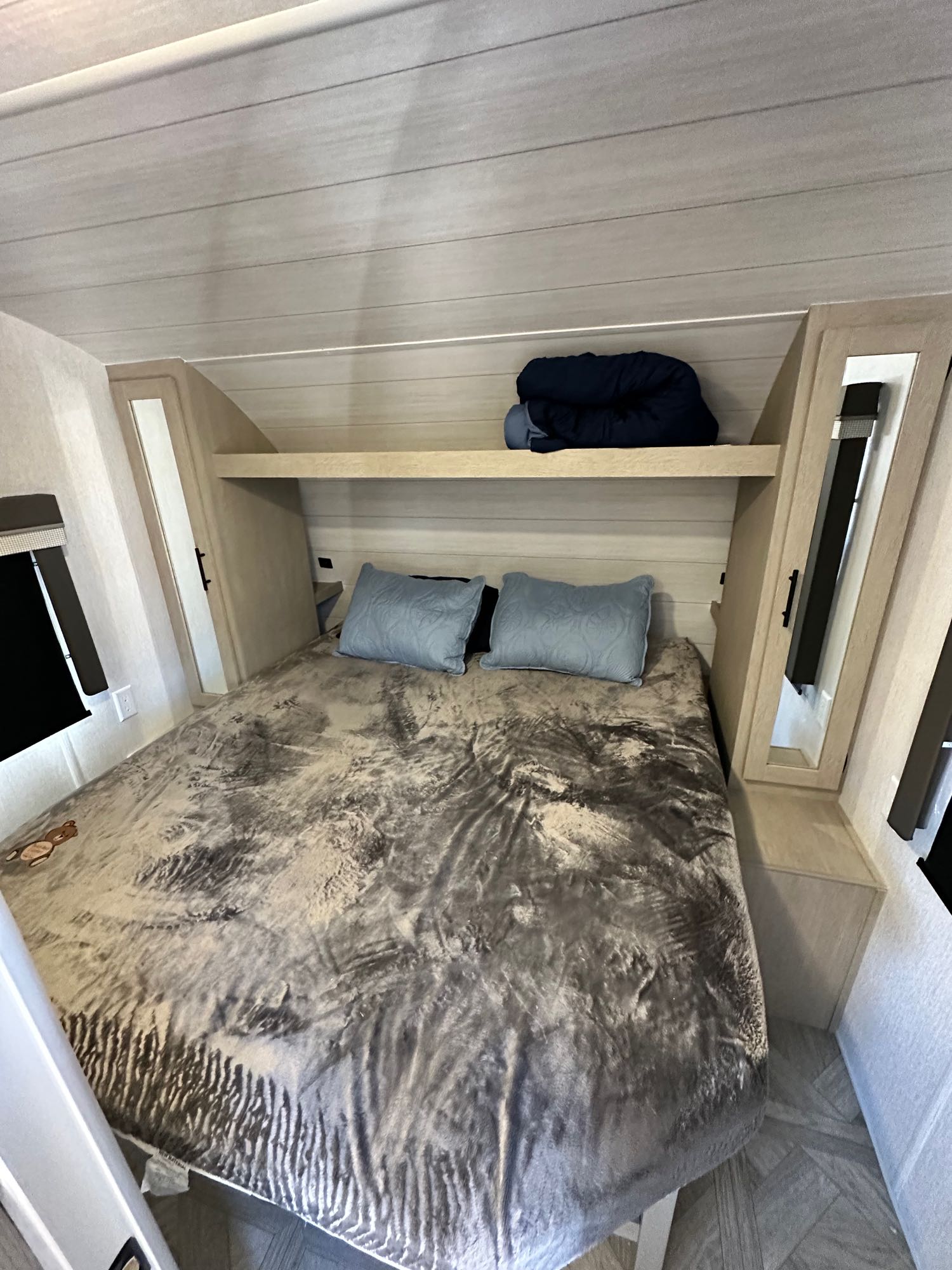 RV rental's cozy bedroom features a spacious bed with a patterned gray blanket, blue pillows, and built-in storage.. Forest River Salem Cruise Lite T282QXBL 2023