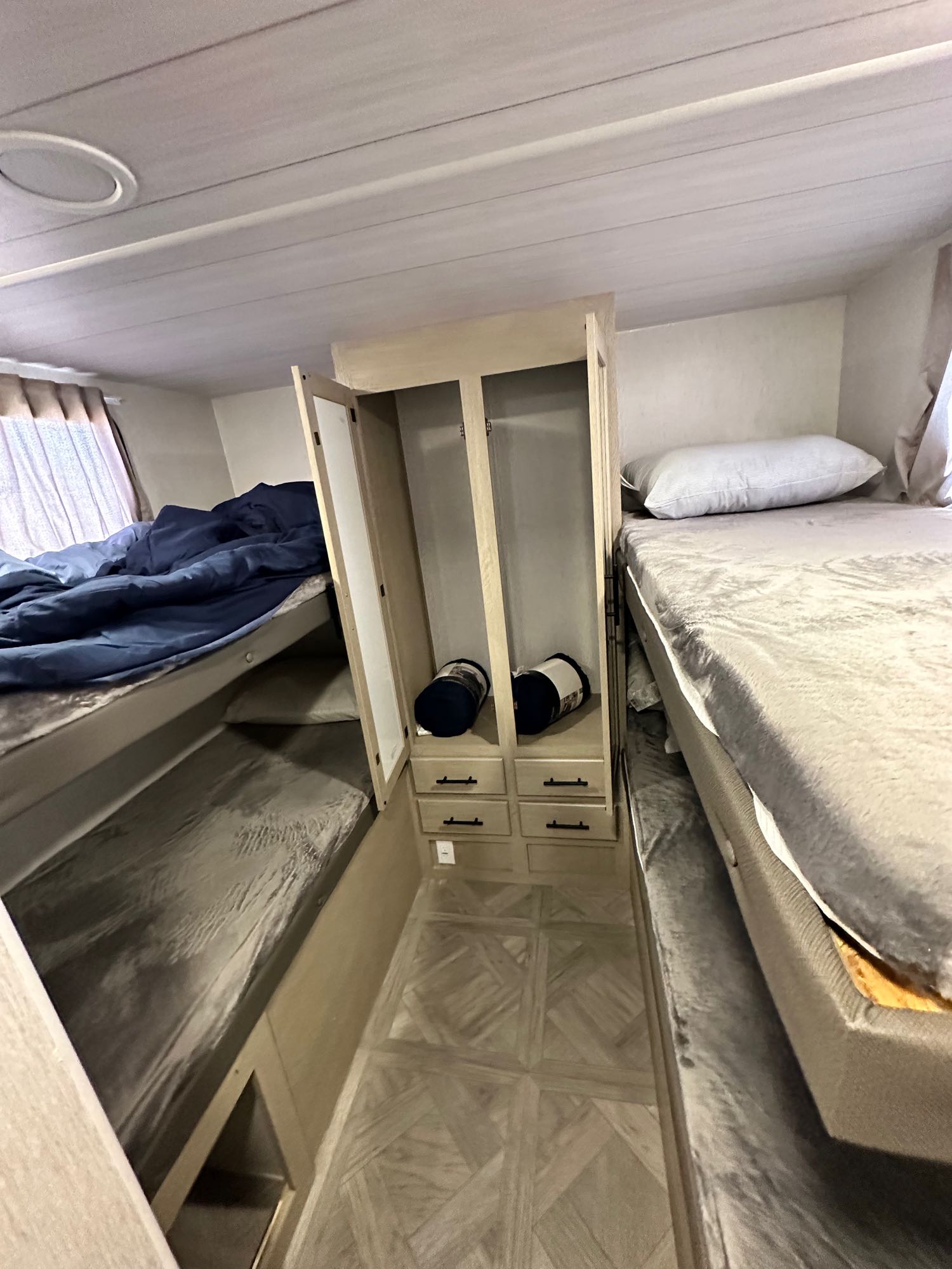 Cozy RV rental interior featuring bunk beds, a central storage cabinet, and patterned flooring for comfortable travel.. Forest River Salem Cruise Lite T282QXBL 2023