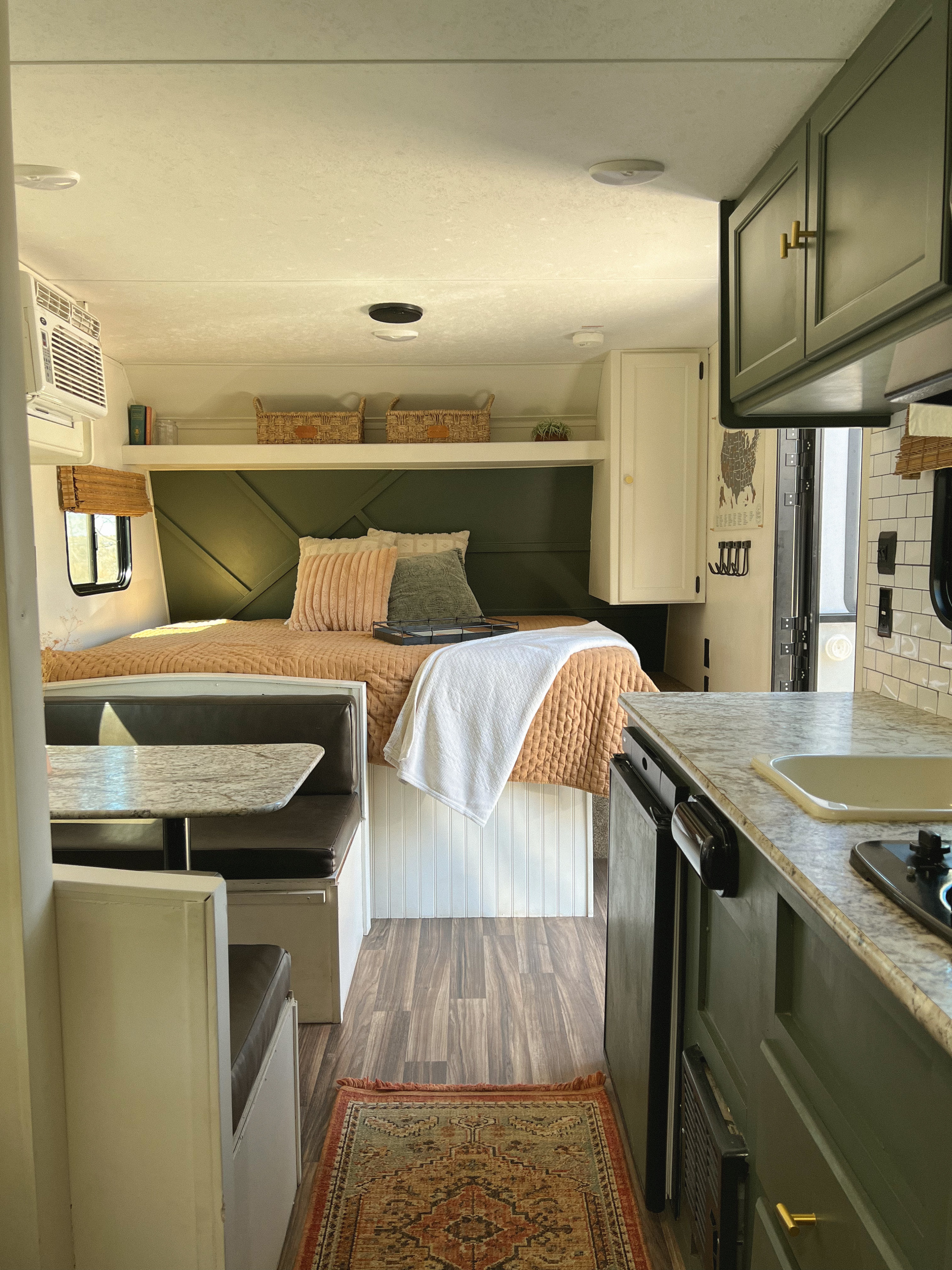 Step inside this inviting RV rental: bedroom with green accents, cozy dinette, and sleek kitchen. Your adventure awaits!. Keystone RV Hideout 2018