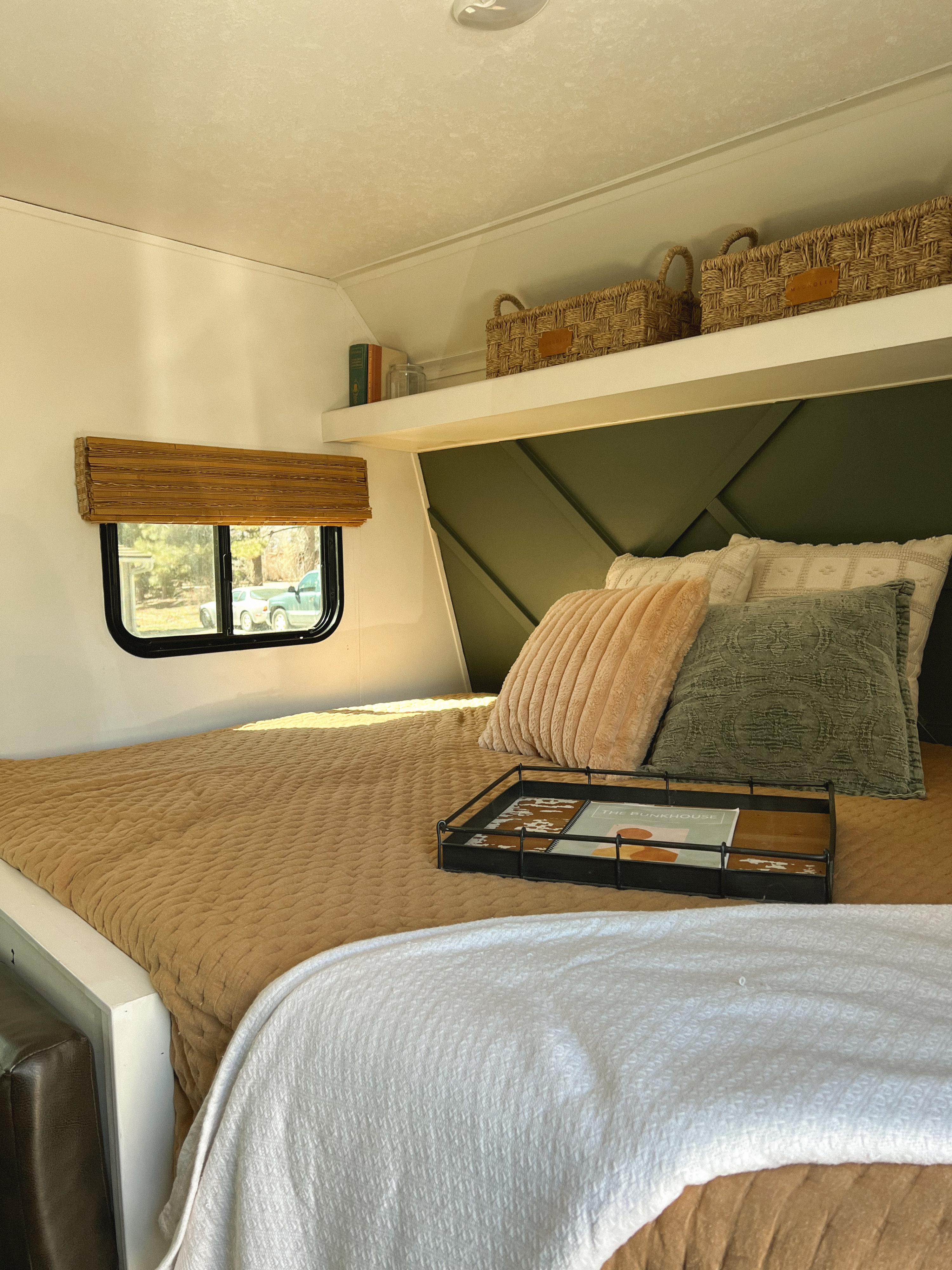 An inviting RV rental bedroom with a custom green headboard, storage shelf, and plush bedding.. Keystone RV Hideout 2018
