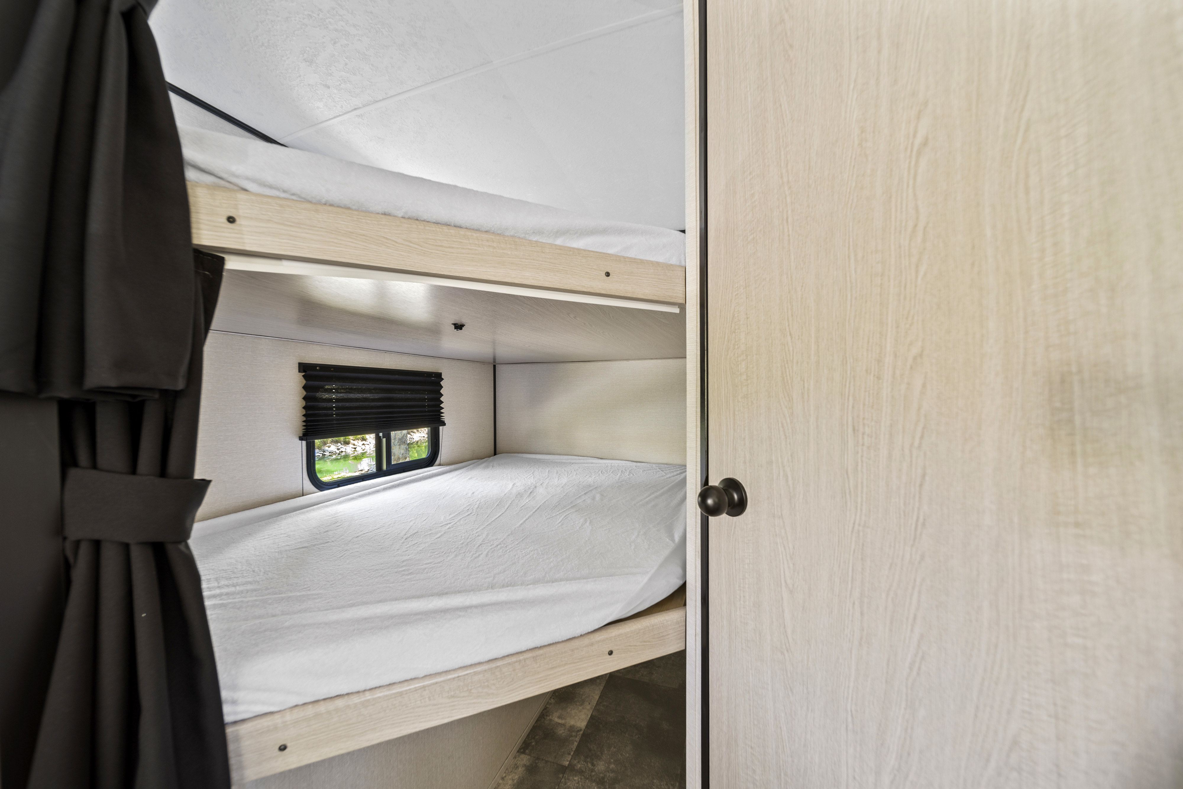 Bunk beds in a bright RV rental, offering cozy sleeping space with a scenic window view.. Coachmen Apex 2022