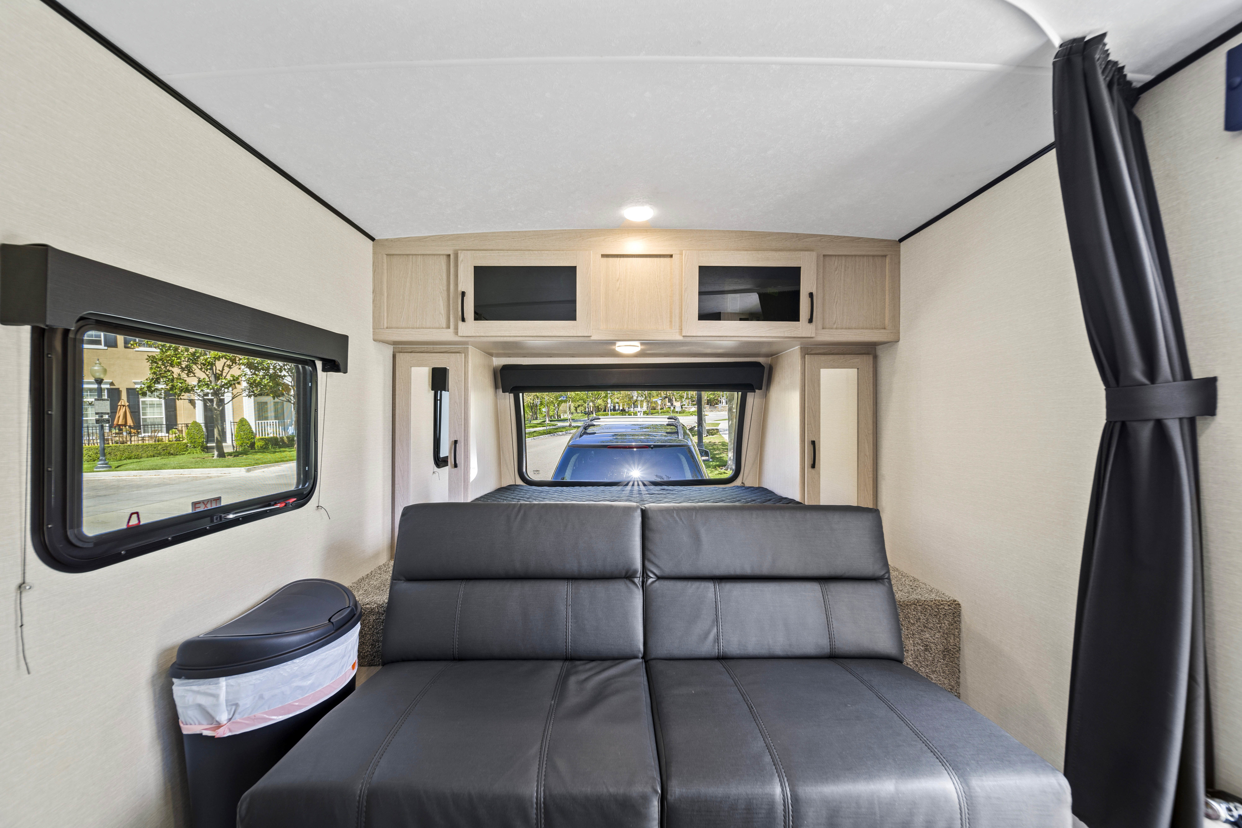 Modern RV rental interior with a versatile sofa bed, overhead cabinets, and large windows for scenic views.. Coachmen Apex 2022
