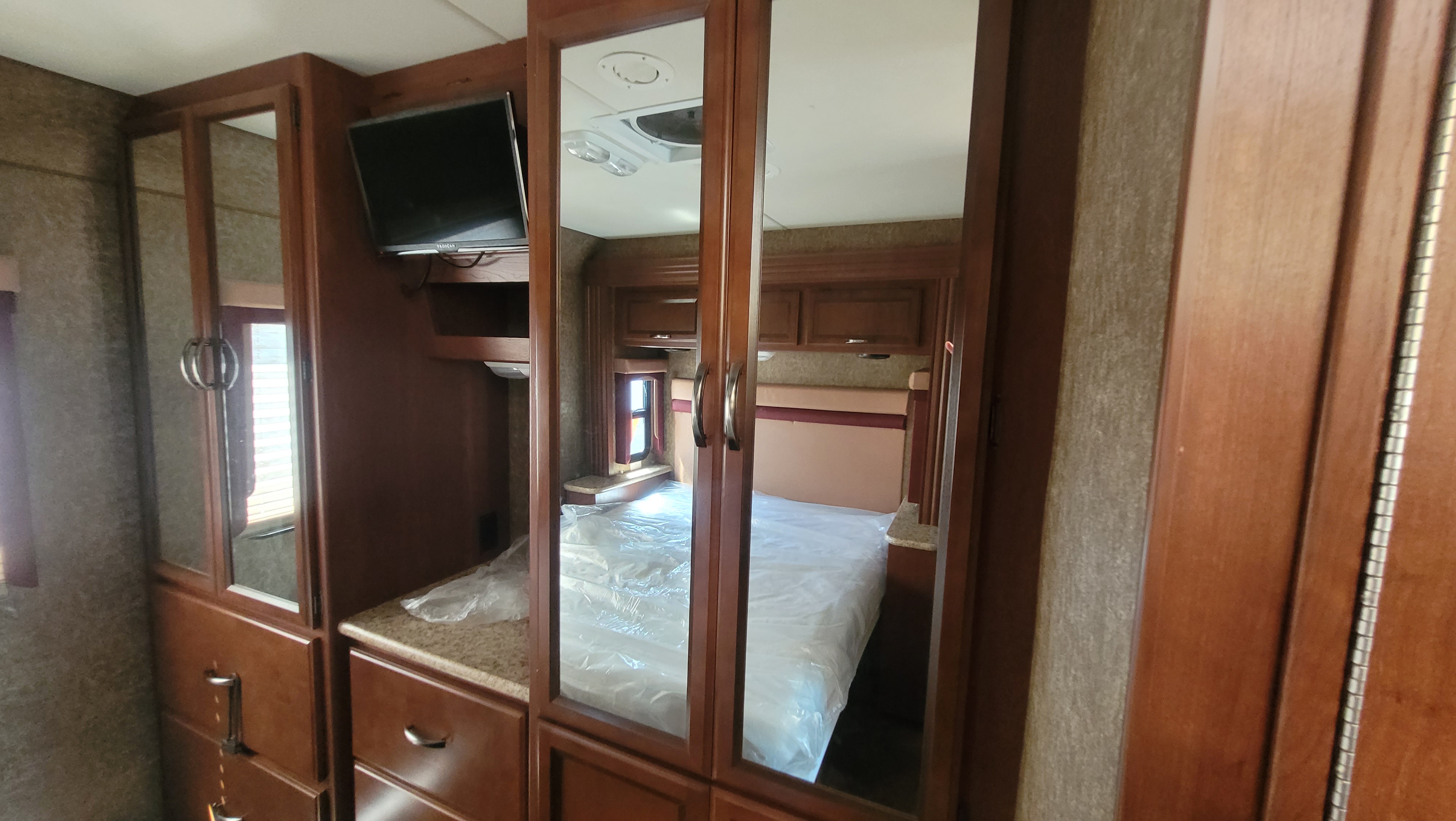 Spacious RV rental bedroom with TV, mirrored wardrobe, and ample storage. Perfect for your next adventure!. A.C.E. A.C.E. Motorhome 2014