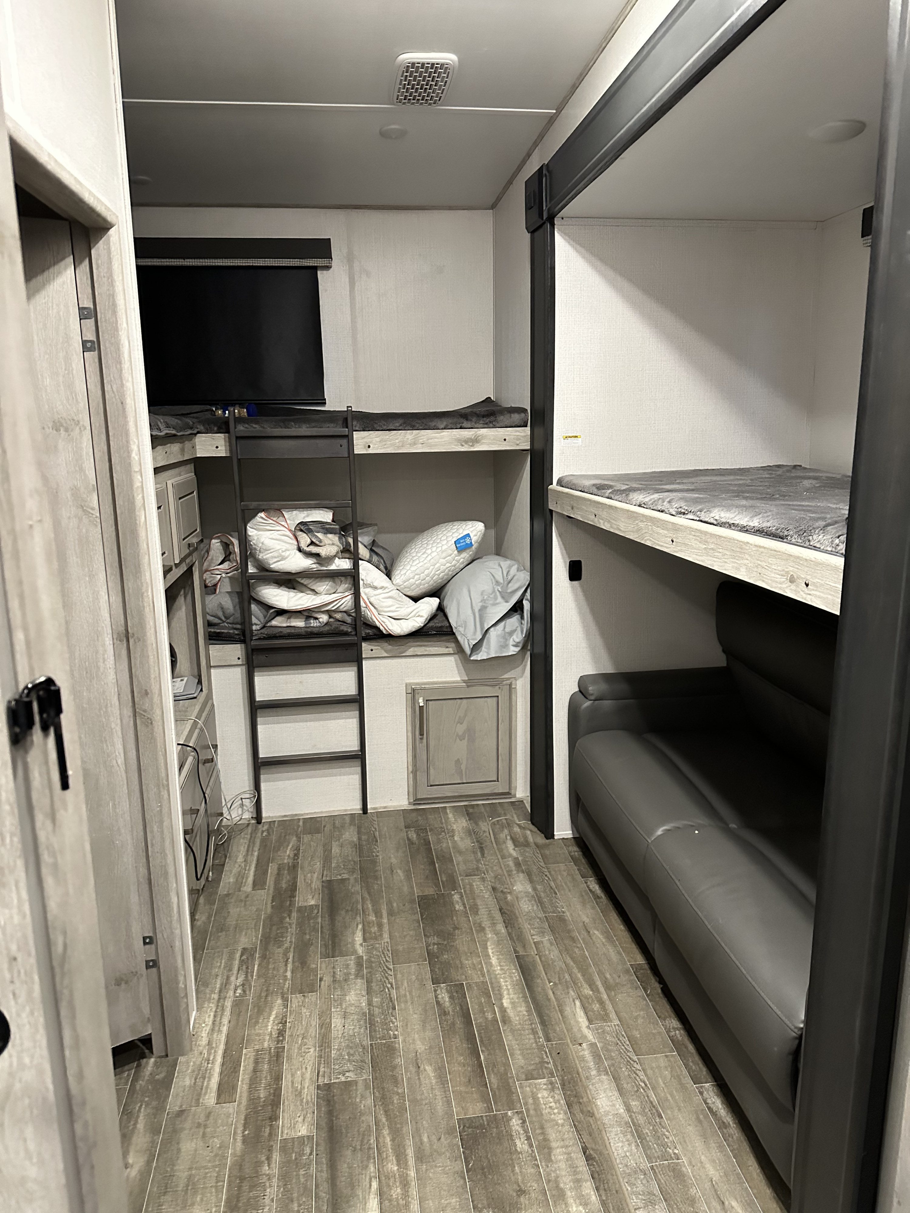 RV rental bunkhouse interior, featuring multiple beds, a TV, and a sofa for comfortable travel.. Keystone RV Avalanche 2022