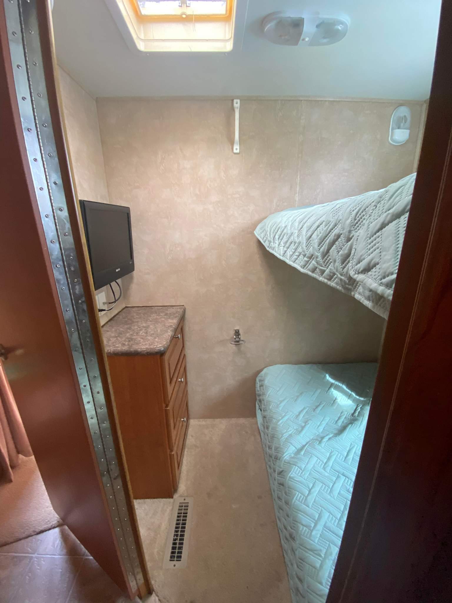 Compact RV rental bedroom featuring two bunk beds with blue quilts, a wall-mounted TV, and a small dresser.. Georgetown M-379 2009