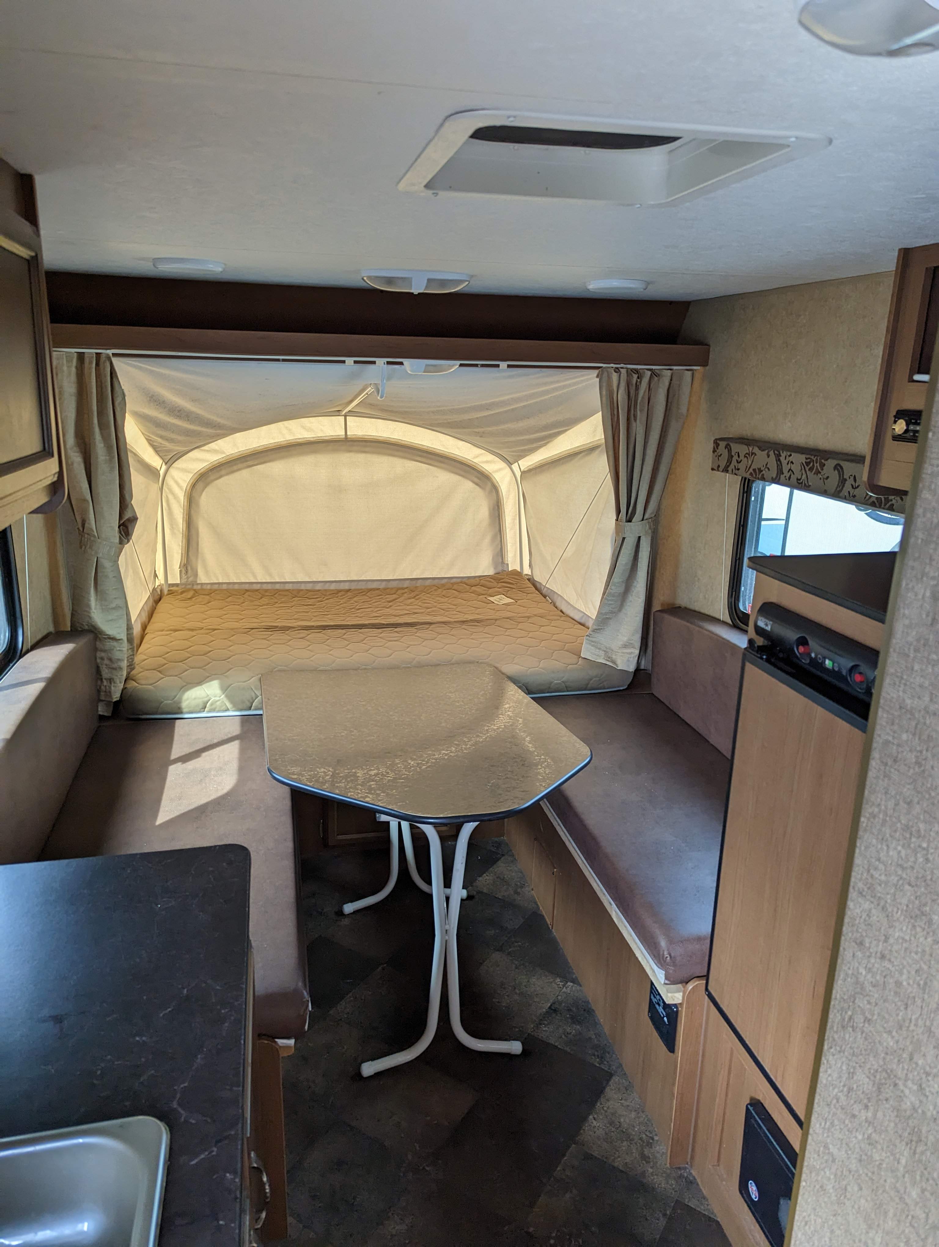 RV rental interior showing a pop-up bed, a dining area with table, and a small kitchen sink on the left.. Starcraft AR-One 2014