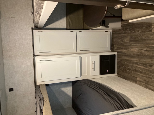 Spacious RV rental interior: bunk beds, sleek white cabinetry, and an electrical control panel for travelers.. Keystone RV Bullet Ultra Lite 2021