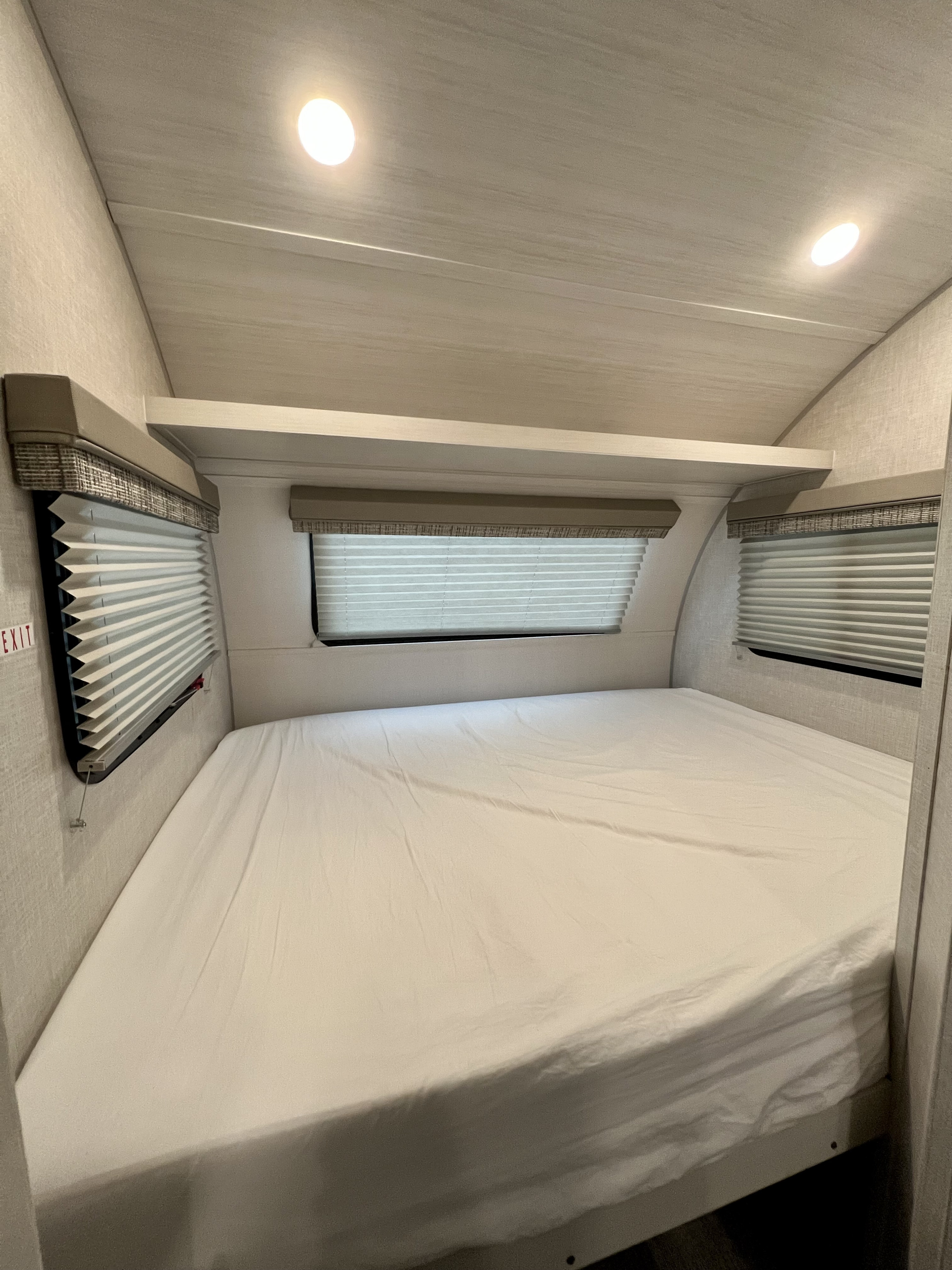 Spacious RV rental bedroom featuring a large bed, pleated window blinds, and bright overhead lighting for comfortable travel.. Forest River R-Pod RP-190 2021