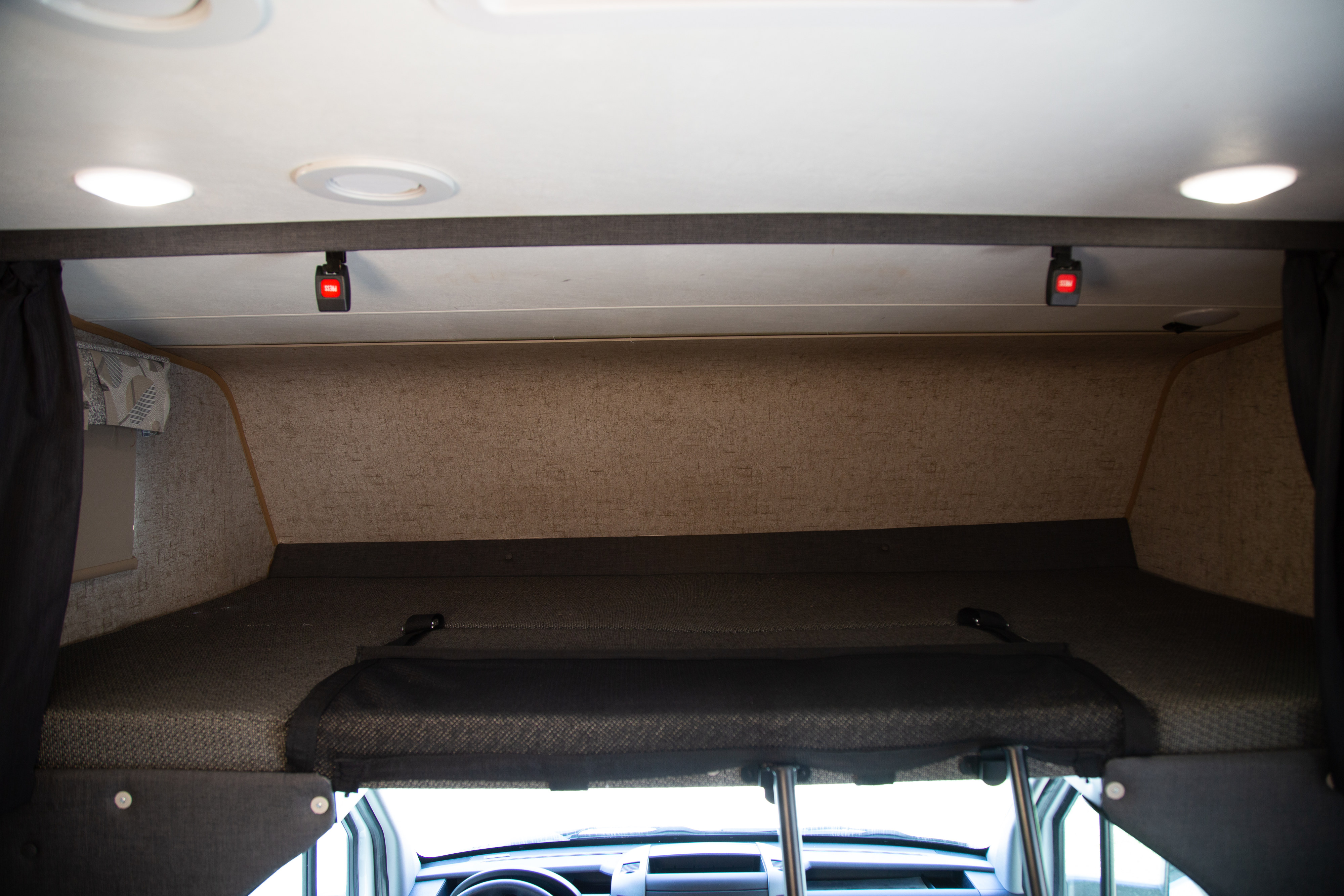 Spacious cab-over bunk sleeping area in an RV rental, featuring a safety net and bright interior lighting for comfort.. Forest River Coachmen Prism 2018