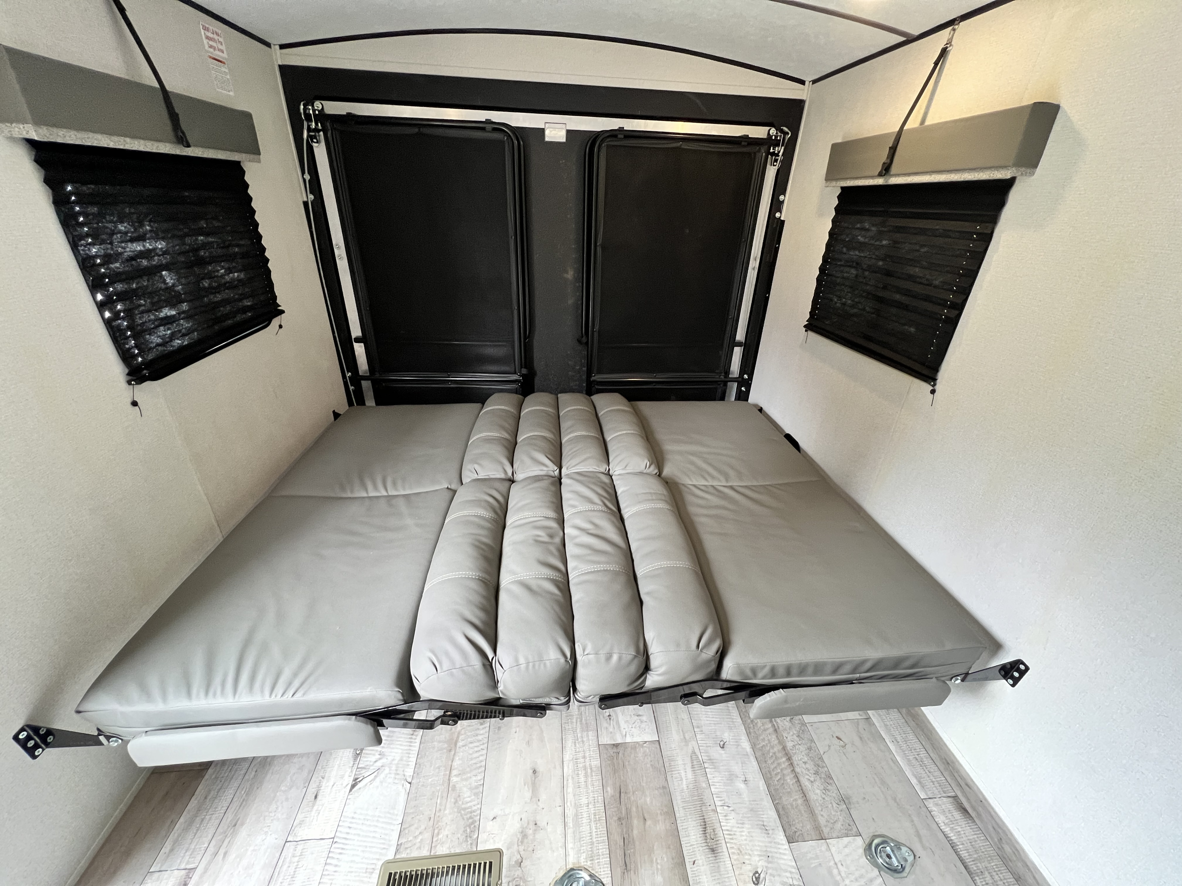 Spacious RV rental interior with a versatile grey bed/seating arrangement & rear cargo doors.. Keystone Springdale 2021