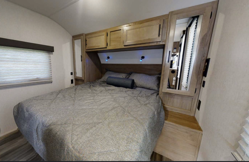 RV rental: Cozy bedroom with a large bed, built-in wooden cabinets, mirrored wardrobes, and subtle blue lighting.. Forest River Cherokee Grey Wolf 2022