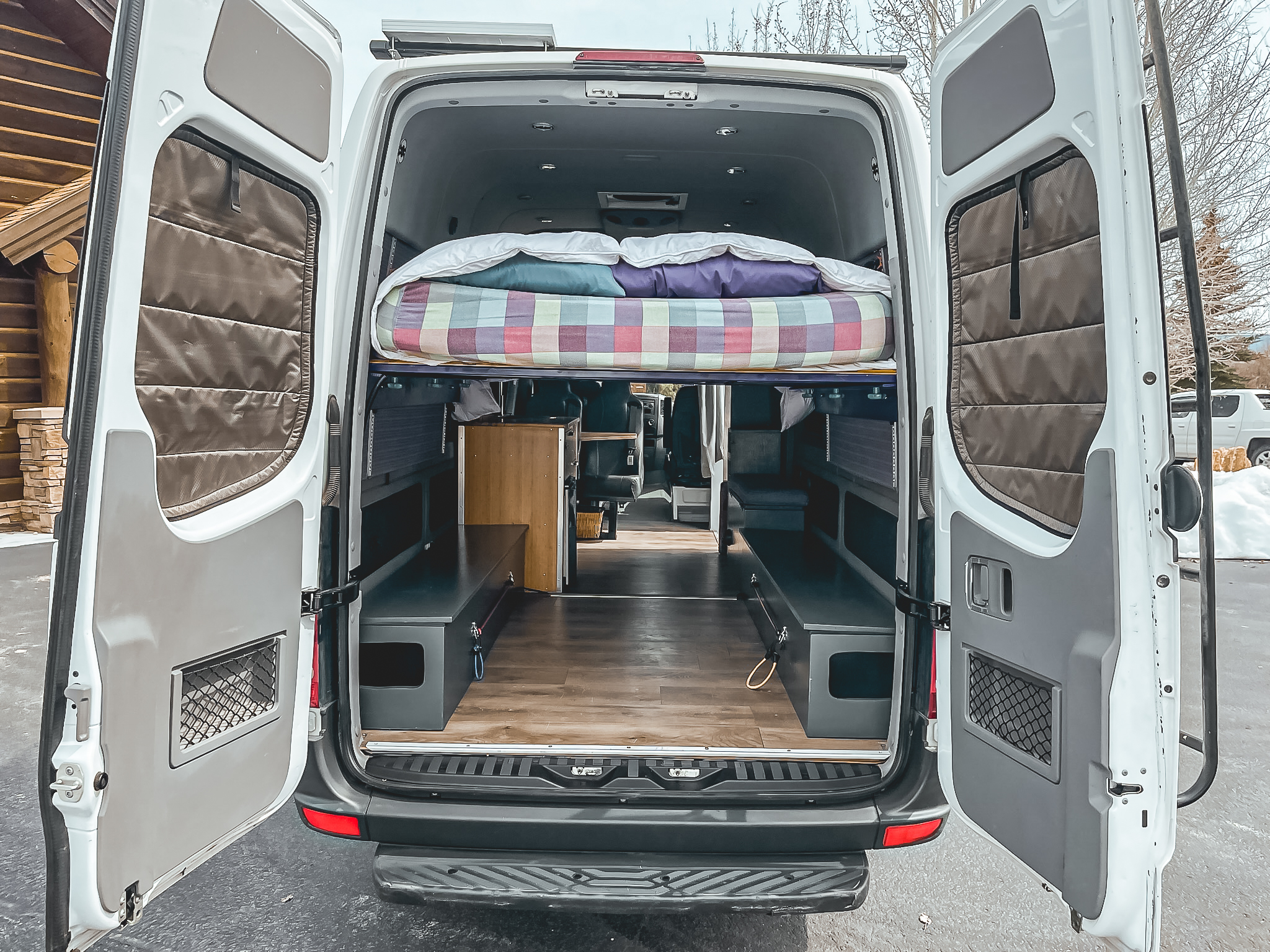 Open **RV rental** conversion van: reveals a cozy interior with a raised bed, storage benches, and wood flooring.. Mercedes-Benz Sprinter 2012