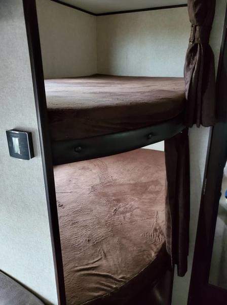 Cozy bunk beds with brown bedding in this RV rental provide comfortable, compact sleeping.. Jayco Jay Flight SLX 2019