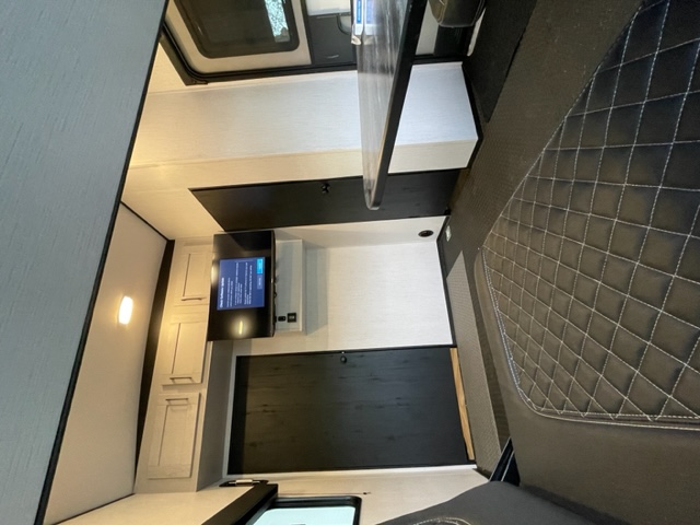 RV rental interior: A cozy space featuring a diamond-stitched bed, wall-mounted TV, and modern black & white design.. Heartland Torque 2023
