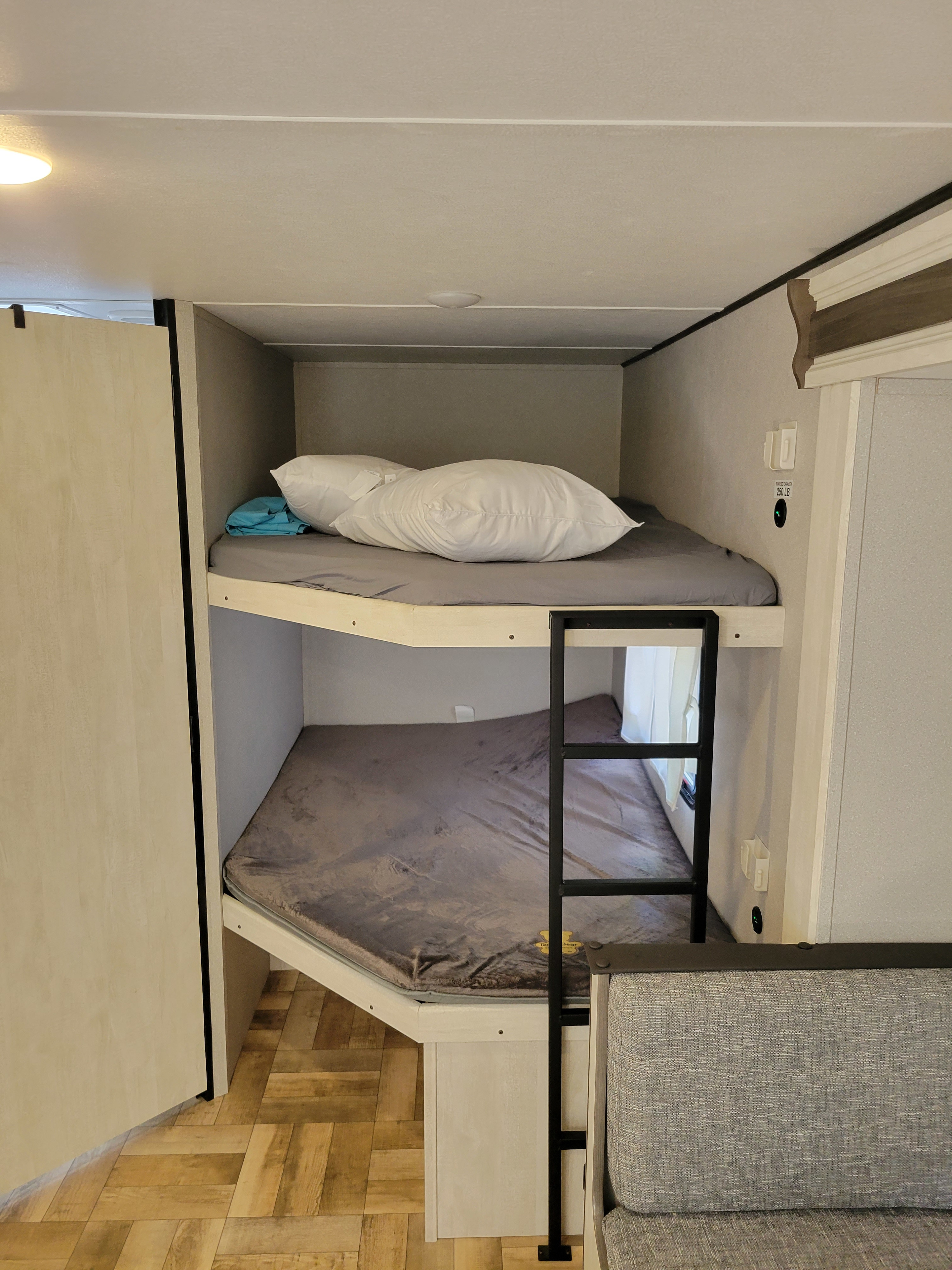 An RV rental's bunk beds, with a ladder & bedding. Max capacity 250lb. Comfy sleeping arrangements.. Forest River Shasta Phoenix Lite 2023