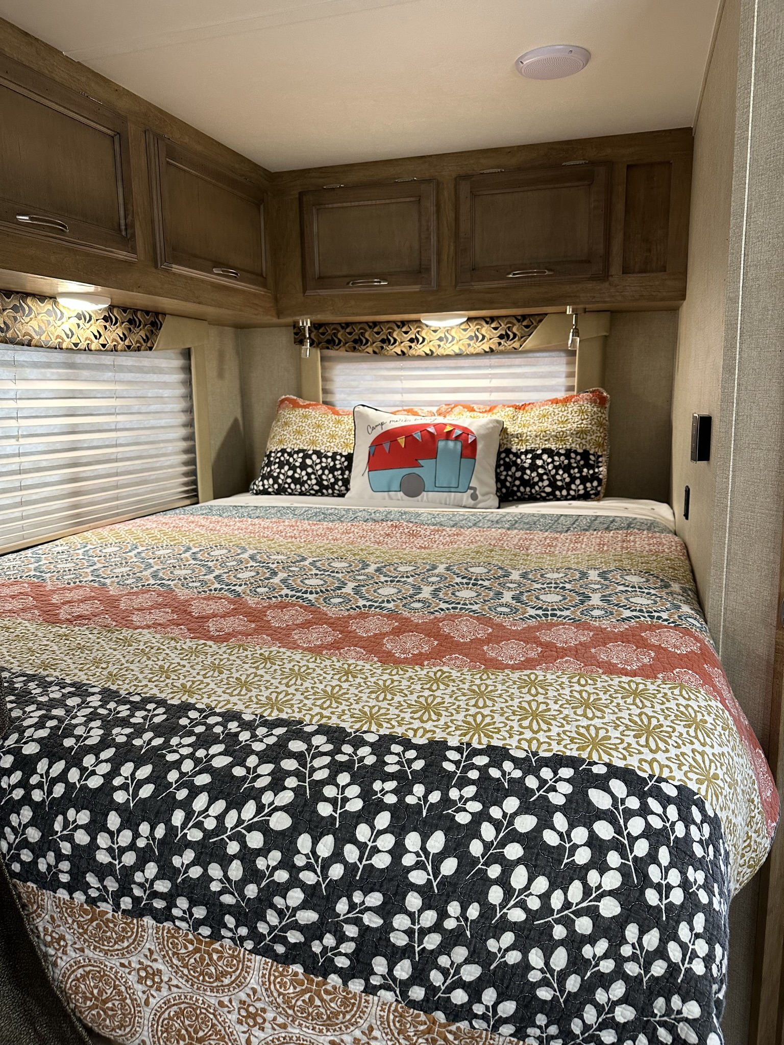 RV rental bedroom: A vibrant quilted bed, wooden overhead cabinets, and soft lighting create a cozy sleeping space.. Gulf Stream Conquest 2017
