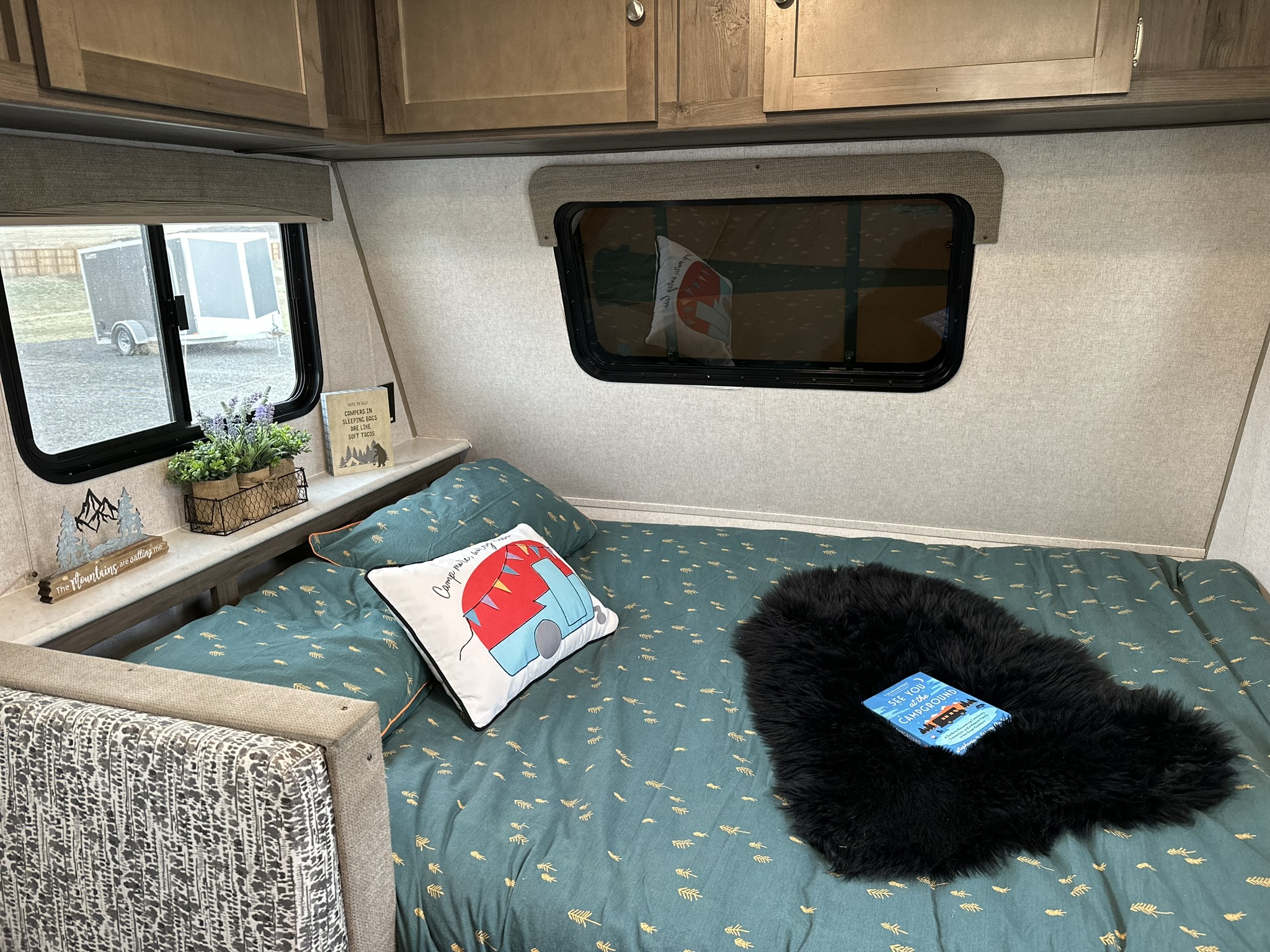 Cozy rv rental camper interior. A comfortable bed with camping decor, a soft throw, and a book await your next adventure.. Forest River Viking 2020