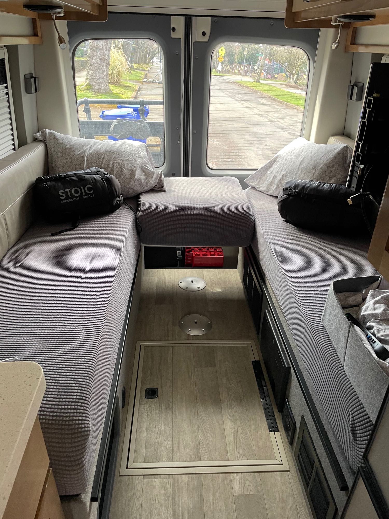 Inside a comfy RV rental: parallel sleeping areas with cushions, central aisle, and windows view to a residential street.. Coachmen Beyond 22D 2020