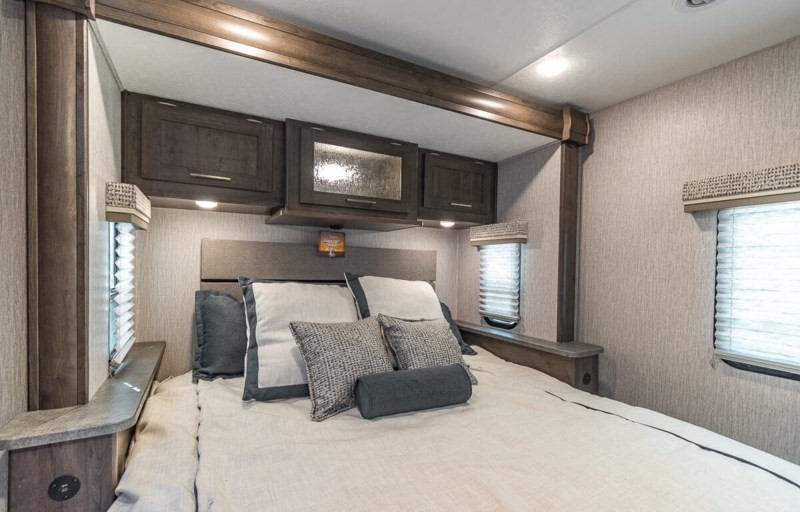 This inviting RV rental bedroom offers a comfortable bed, overhead storage cabinets, and window blinds for a cozy stay.. Coachmen Pursuit 2022