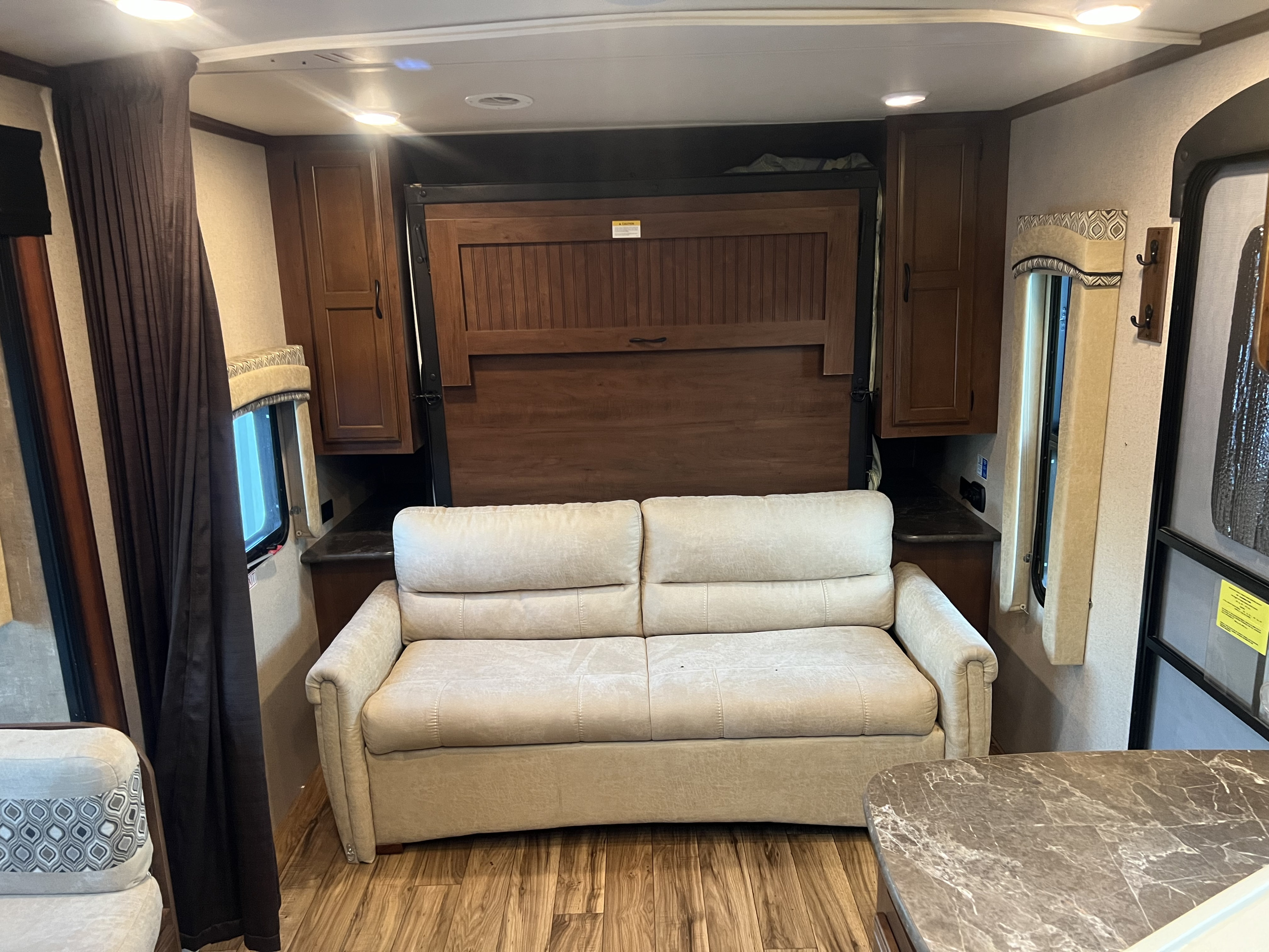 RV rental: Bright interior with a light sofa and dark wood Murphy bed unit, flanked by storage cabinets.. Jayco Jay Flight 2016