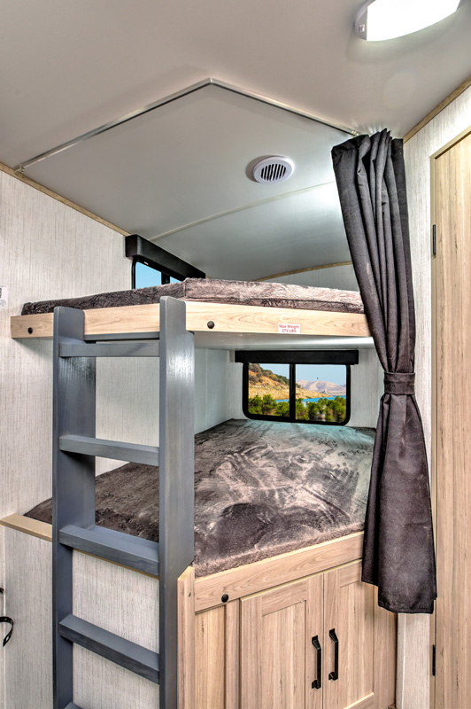 Detailed view of an **RV rental**'s interior with two stacked bunk beds, a ladder, and a window displaying a scenic outdoor landscape.. Heartland RVs Sundance Ultra Lite 2022