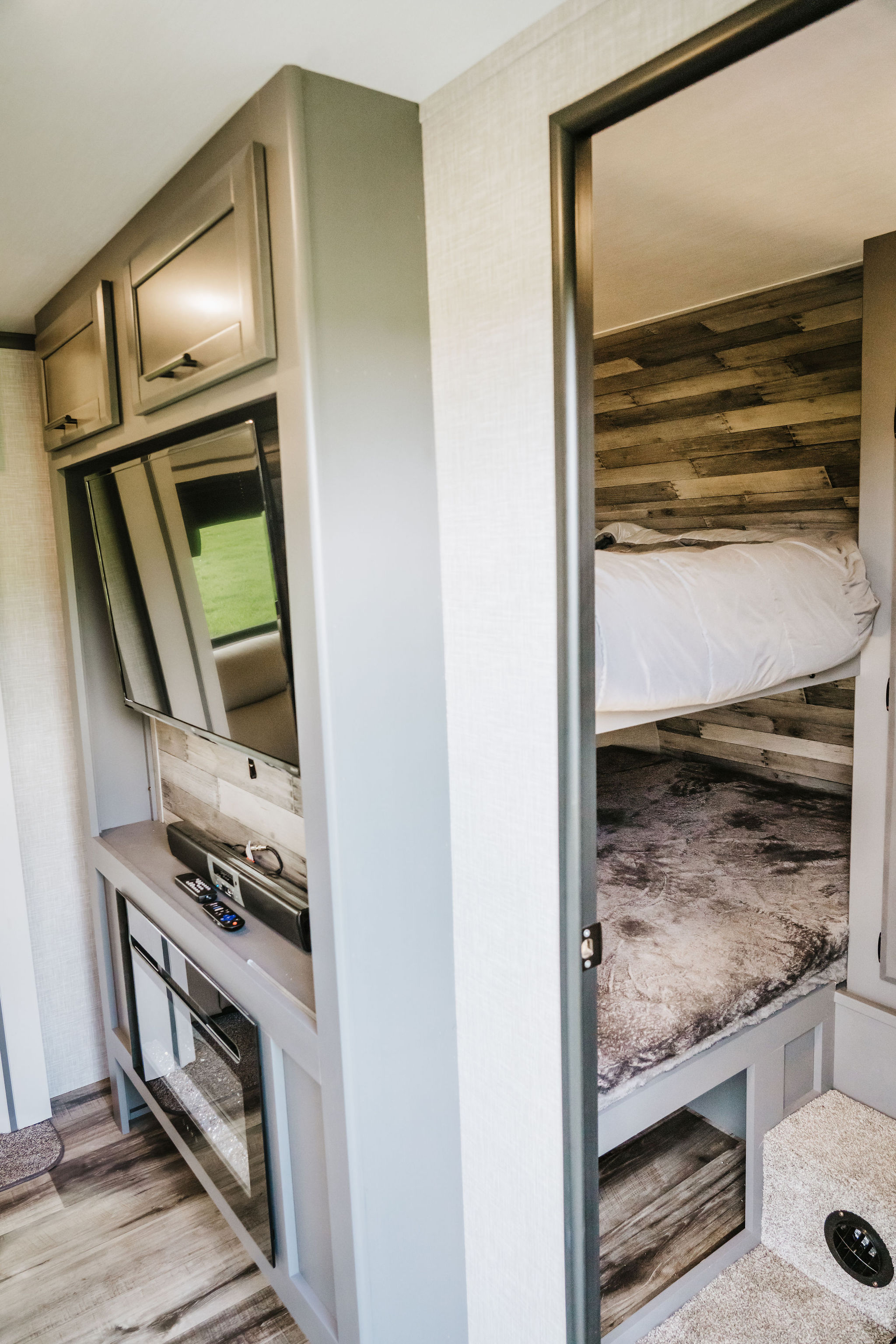 Inside this RV rental: comfortable bunk beds and a built-in media center with TV, designed for compact, enjoyable travel.. Other Other 2023