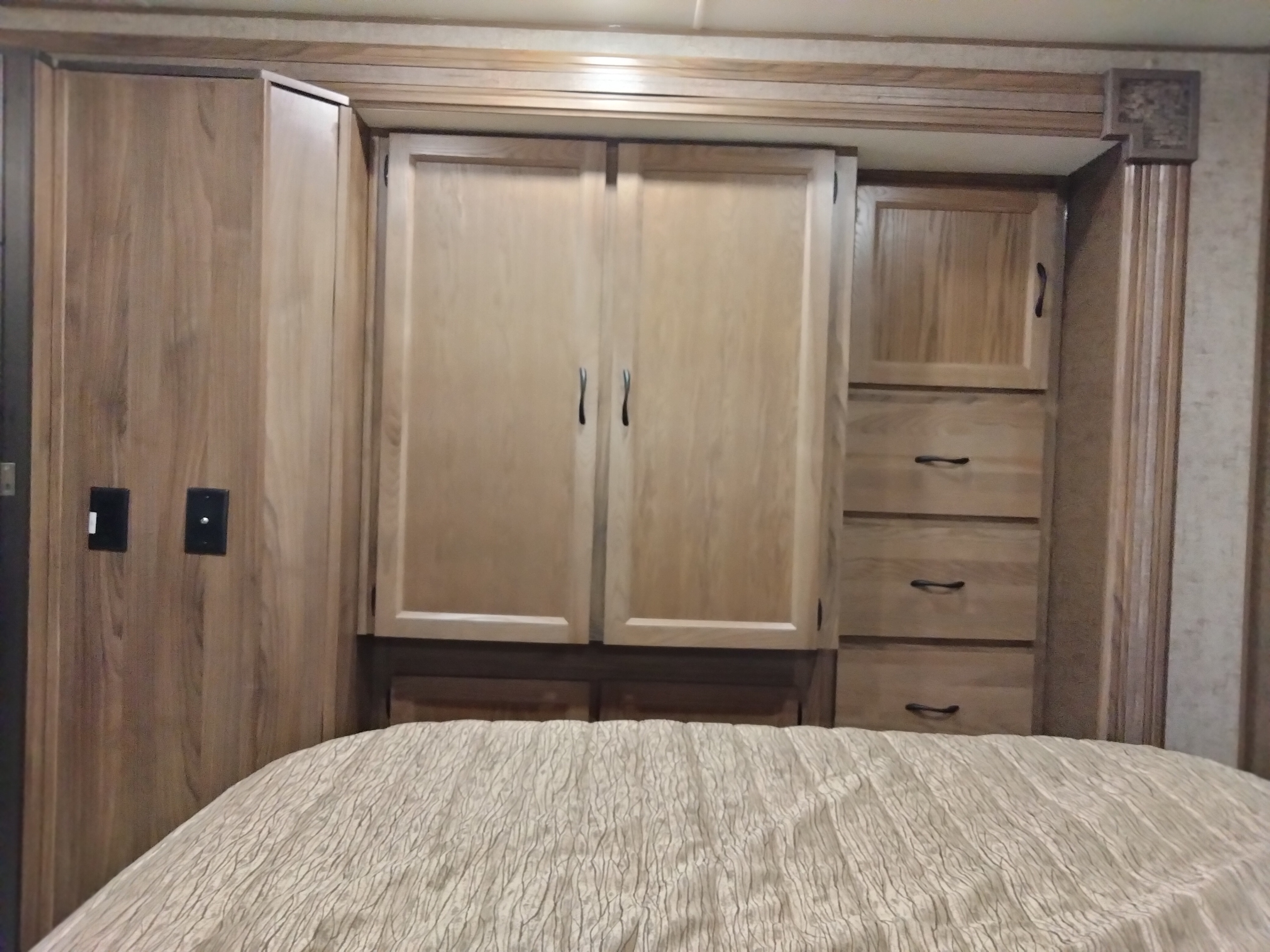 RV rental bedroom interior with wooden cabinets, drawers, and a bed, showcasing practical storage.. Coachmen Freelander 2019