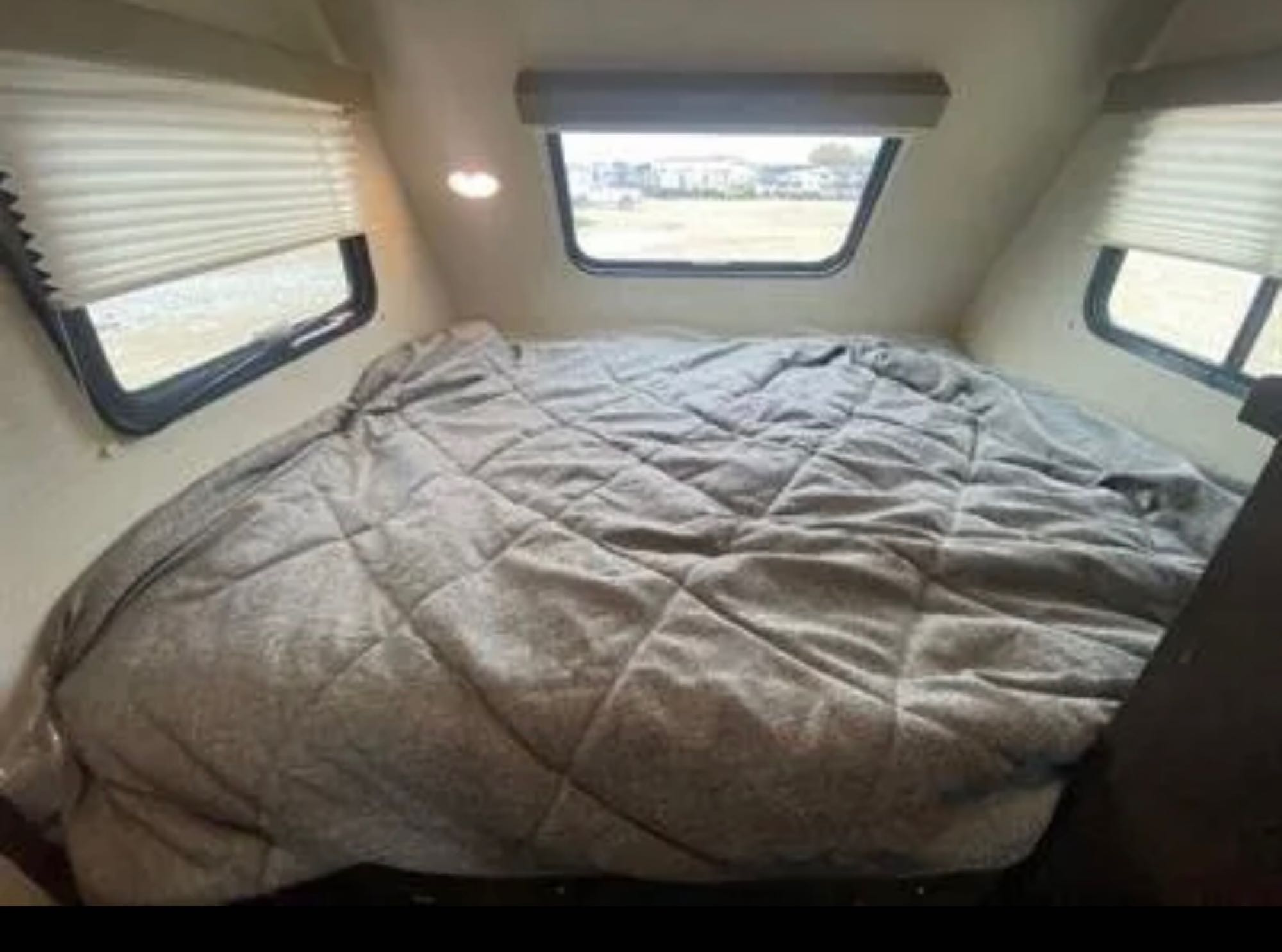 Queen size bed in front of RV. Keystone RV Bullet Colt 2018
