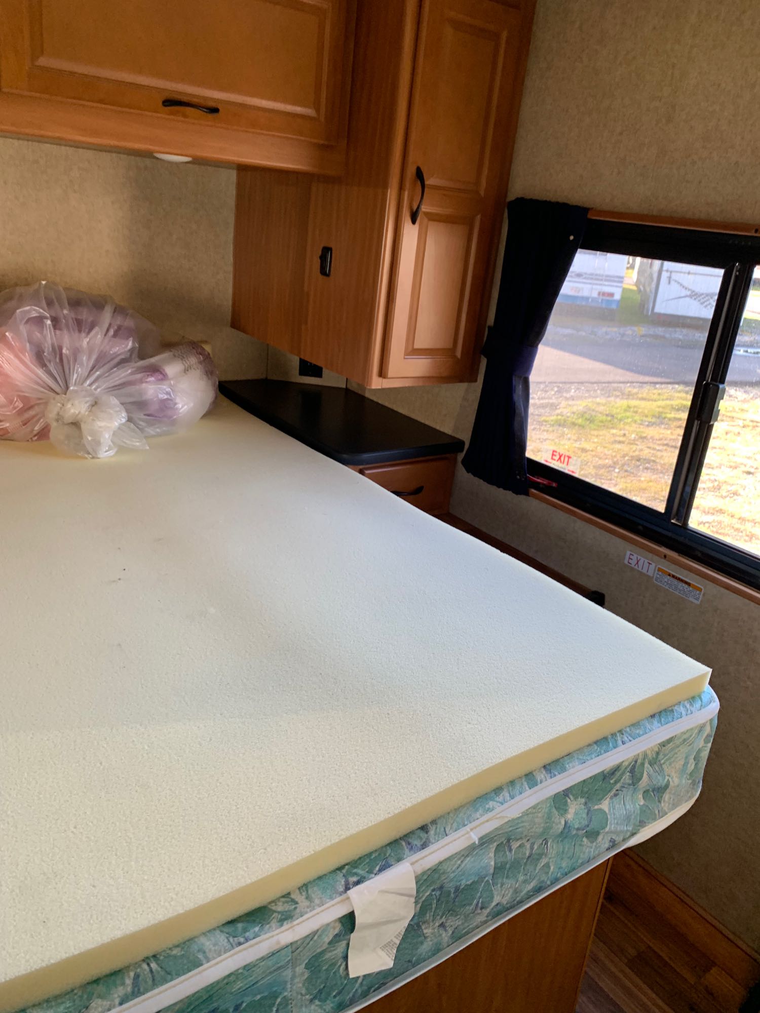 RV rental bedroom: a bed with foam topper, cabinets, and emergency exit window view.. Thor Majestic 2017