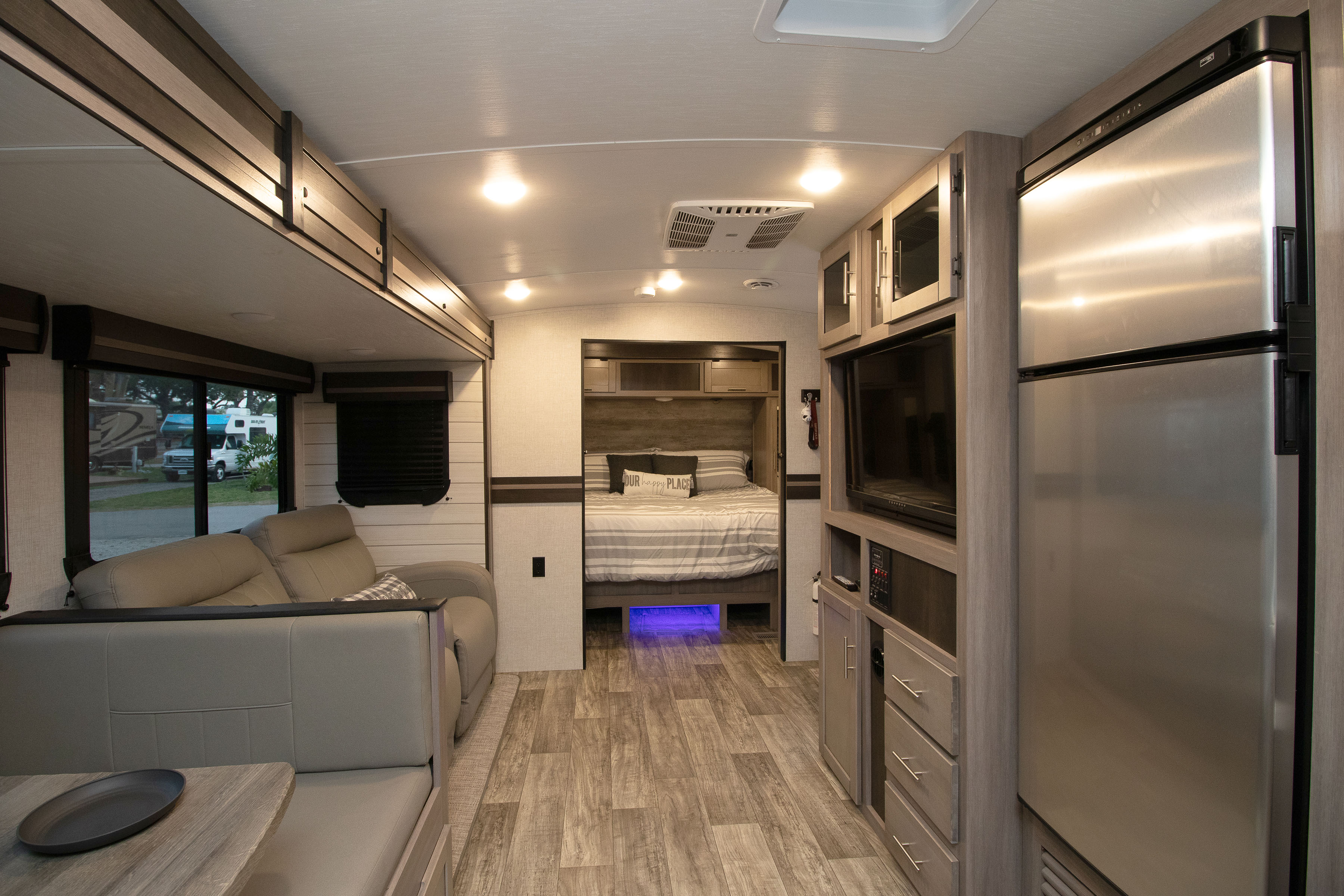 Spacious RV rental interior featuring a bright living area, cozy bedroom with blue lights, and full kitchen. Ideal for travel.. Crossroads RV Sunset Trail Super Lite 2022