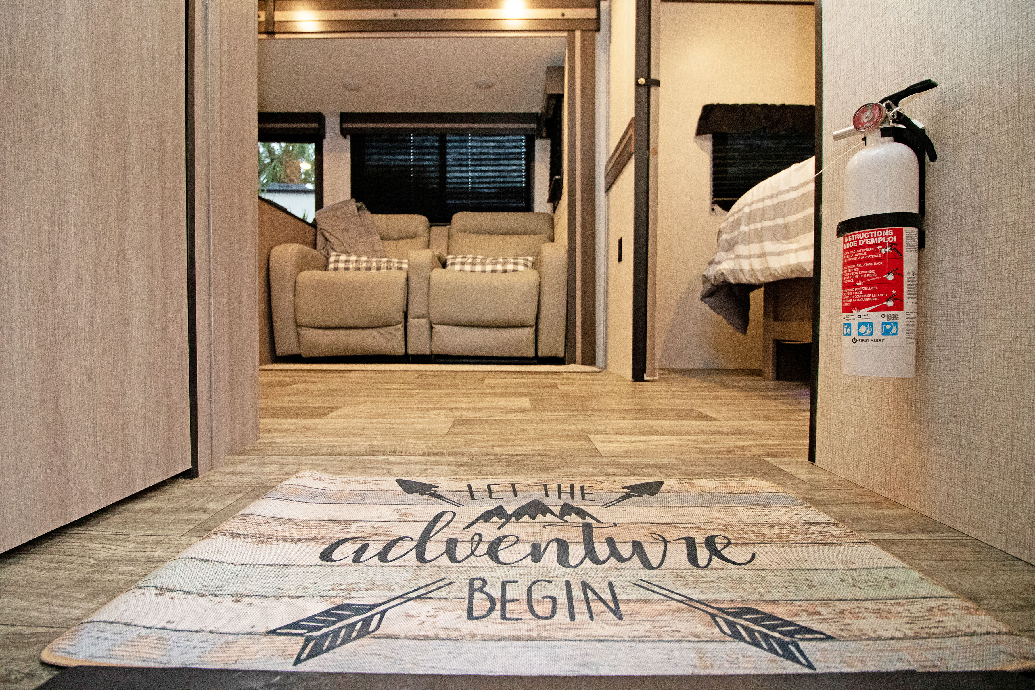 Cozy RV rental interior with "adventure" mat, recliners, bed, and fire extinguisher for a safe journey.. Crossroads RV Sunset Trail Super Lite 2022