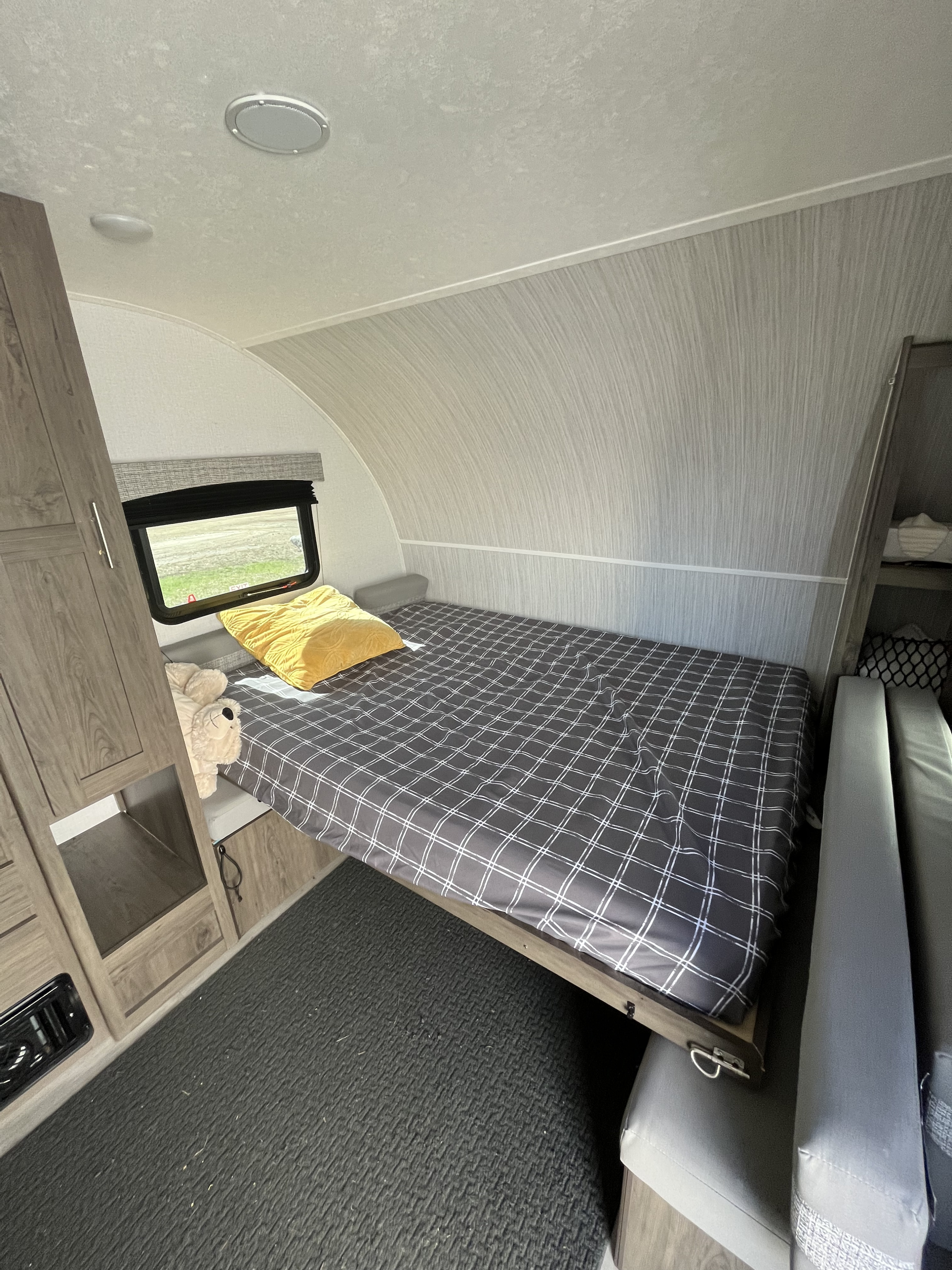 Travel trailer rv rental: a cozy bedroom with plaid bed, yellow pillow, and storage.. Forest River Coachman Clipper 2022