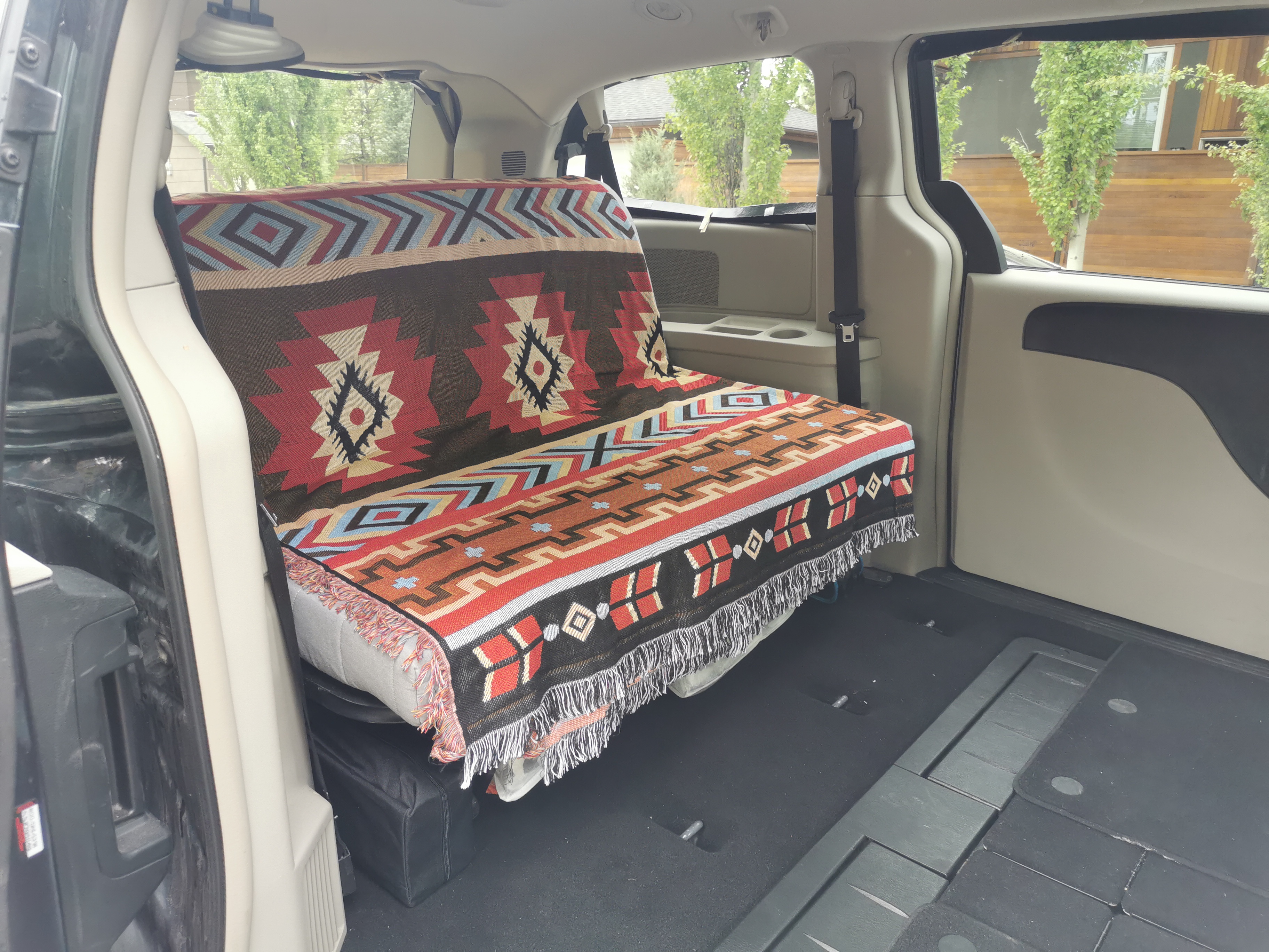 Inside a converted RV rental, a colorful, patterned blanket covers a custom bench/bed in the spacious rear cabin.. Dodge Grand Caravan 2015