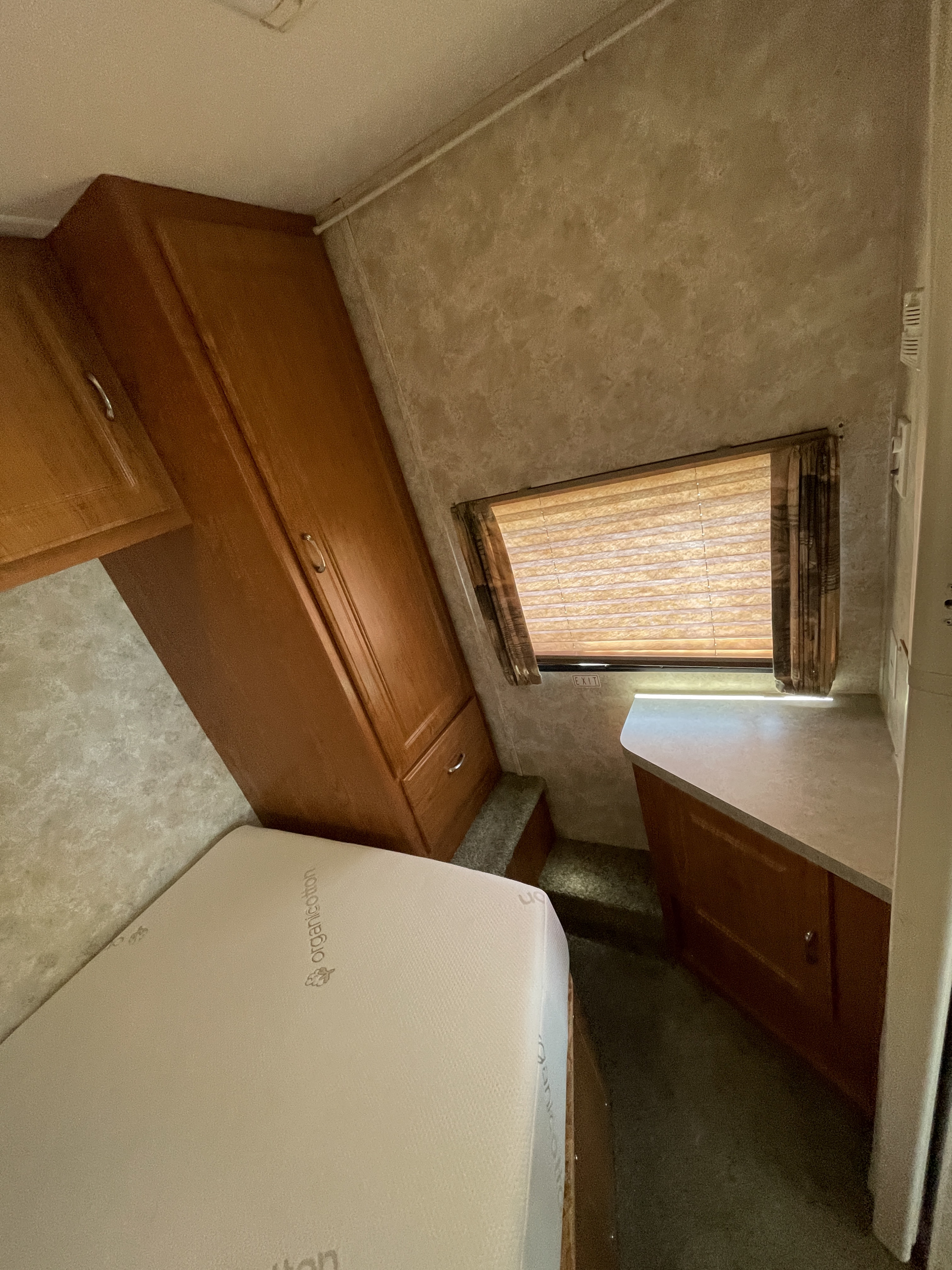 Inside an RV rental: a compact bedroom with a bed, wooden storage, and a window. Perfect for your road trip.. Coachmen Freelander 2004