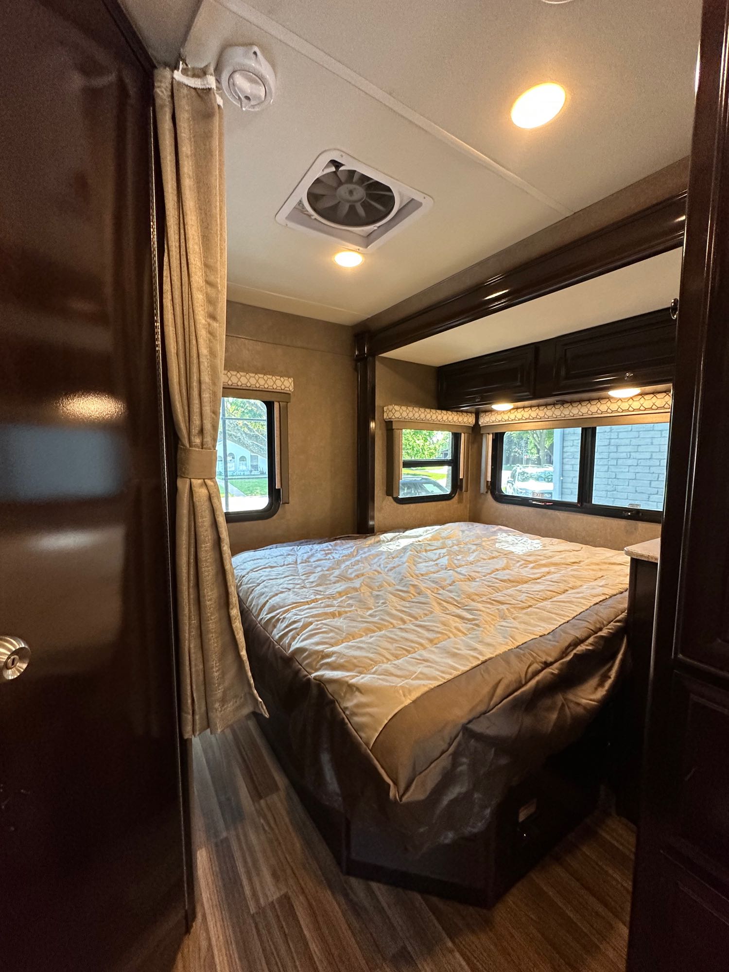 A bright, inviting RV rental bedroom with a large bed, windows, and ceiling fan. Ready for comfortable travel.. Thor Synergy 2018