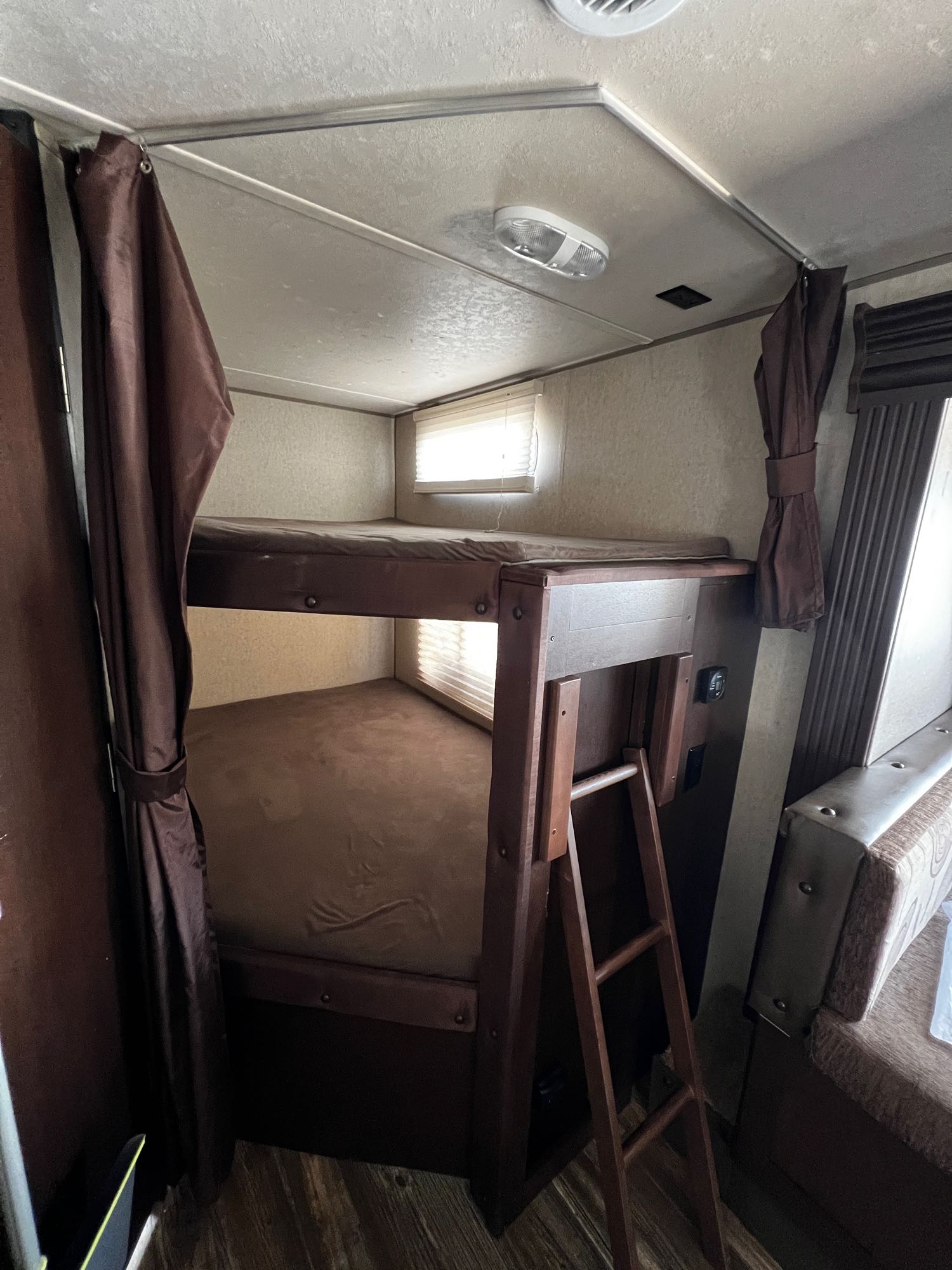 RV rental interior: cozy bunk beds with privacy curtains and a wooden ladder, optimizing space for travelers.. Forest River Forrest River Cherokee Patriot Edition 26DBH 2015