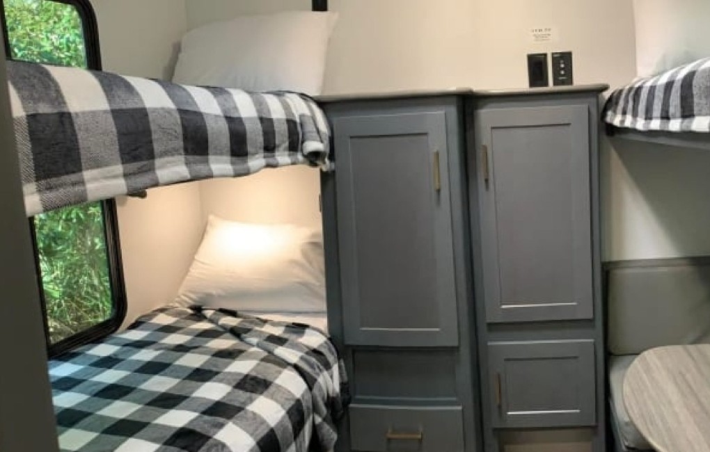 RV rental offers cozy bunk beds with plaid bedding, adjacent storage, and a dinette. Ideal family sleeping.. Keystone RV Bullet Ultra Lite 2022