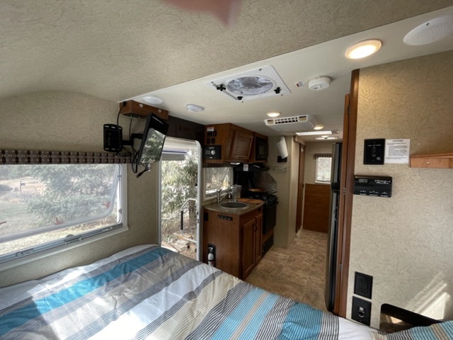 Cozy RV rental interior showcasing a compact kitchen, bed, and bright living area, ideal for travel.. Lance Manufacturing Lance Manufacturing Trailer 2015