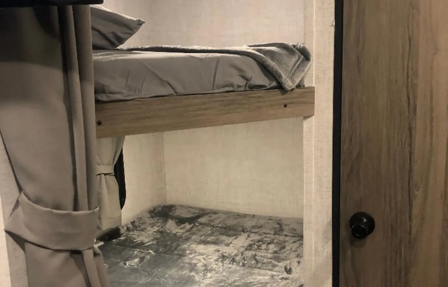 RV rental interior featuring stacked bunk beds with grey bedding and privacy curtains, ideal for campers.. Gulf Stream Ameri-Lite 2022