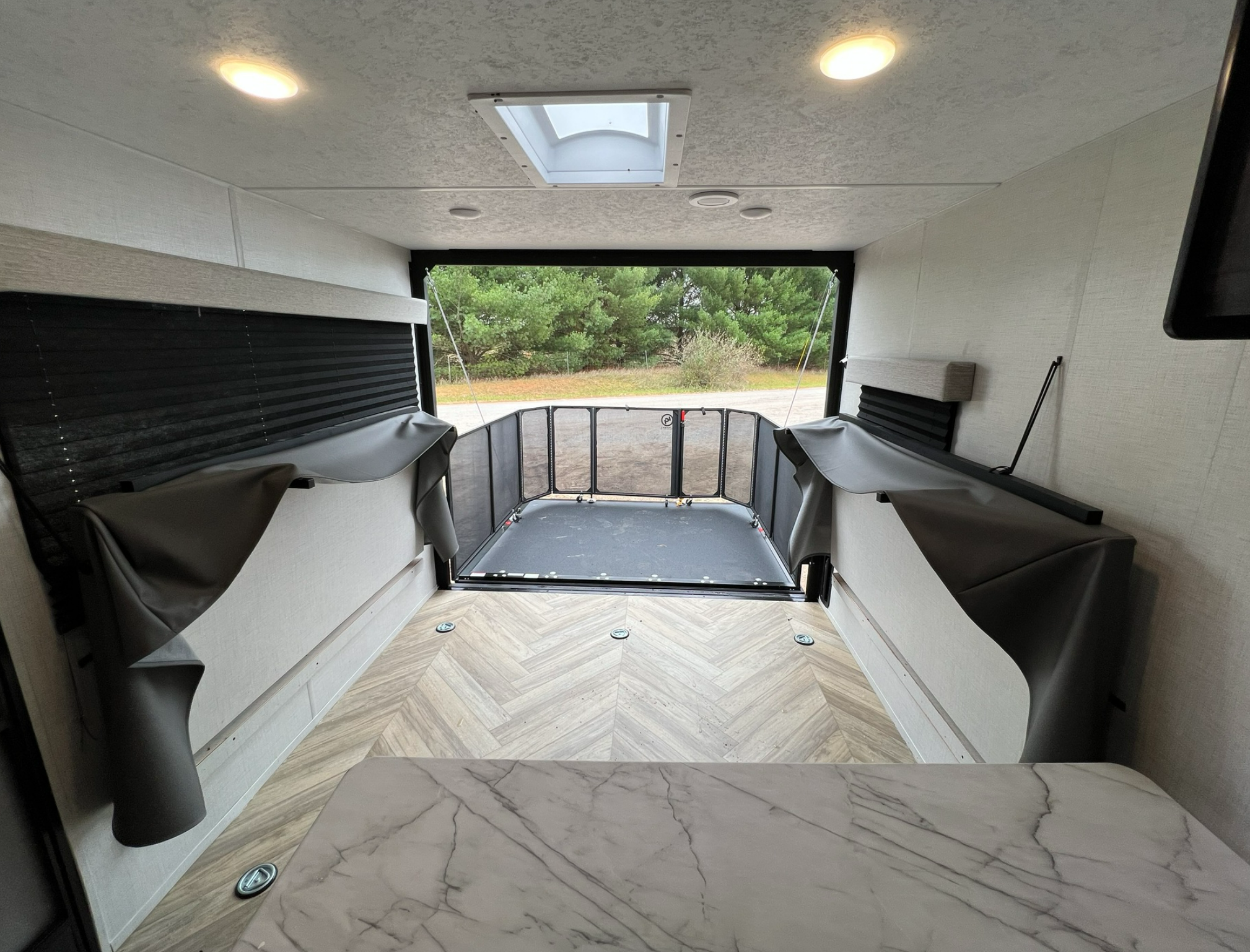 Modern RV rental interior with rear ramp open, revealing a versatile cargo space and fold-up sofas.. Forest River Ozark 2700TH 2022