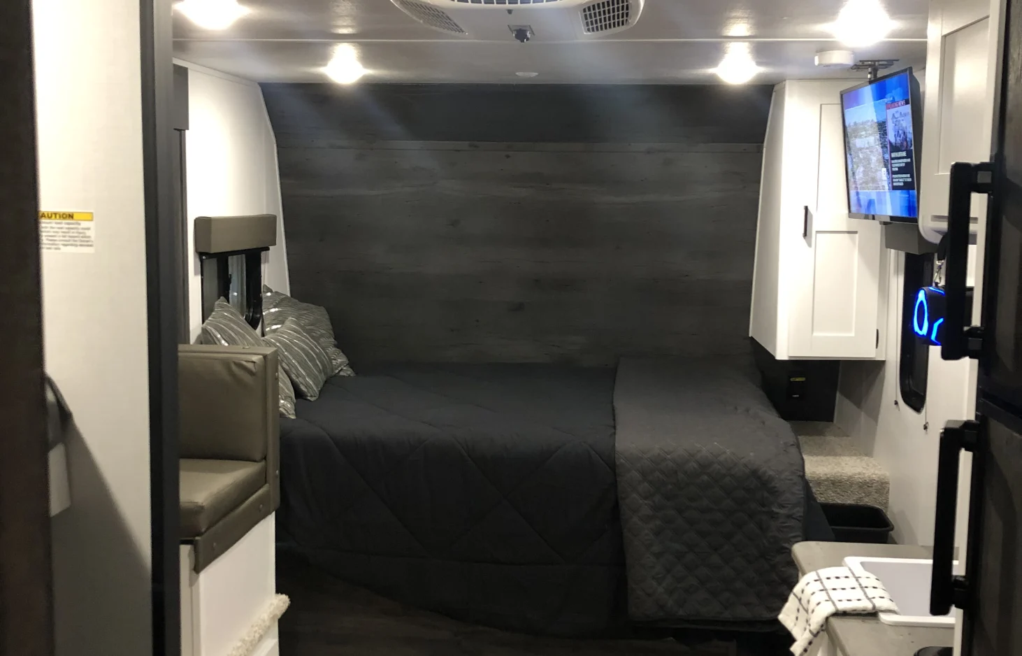 Modern RV rental interior with a cozy bed, seating, TV, and compact kitchen area. Ideal for travel.. Keystone RV Hideout 2022