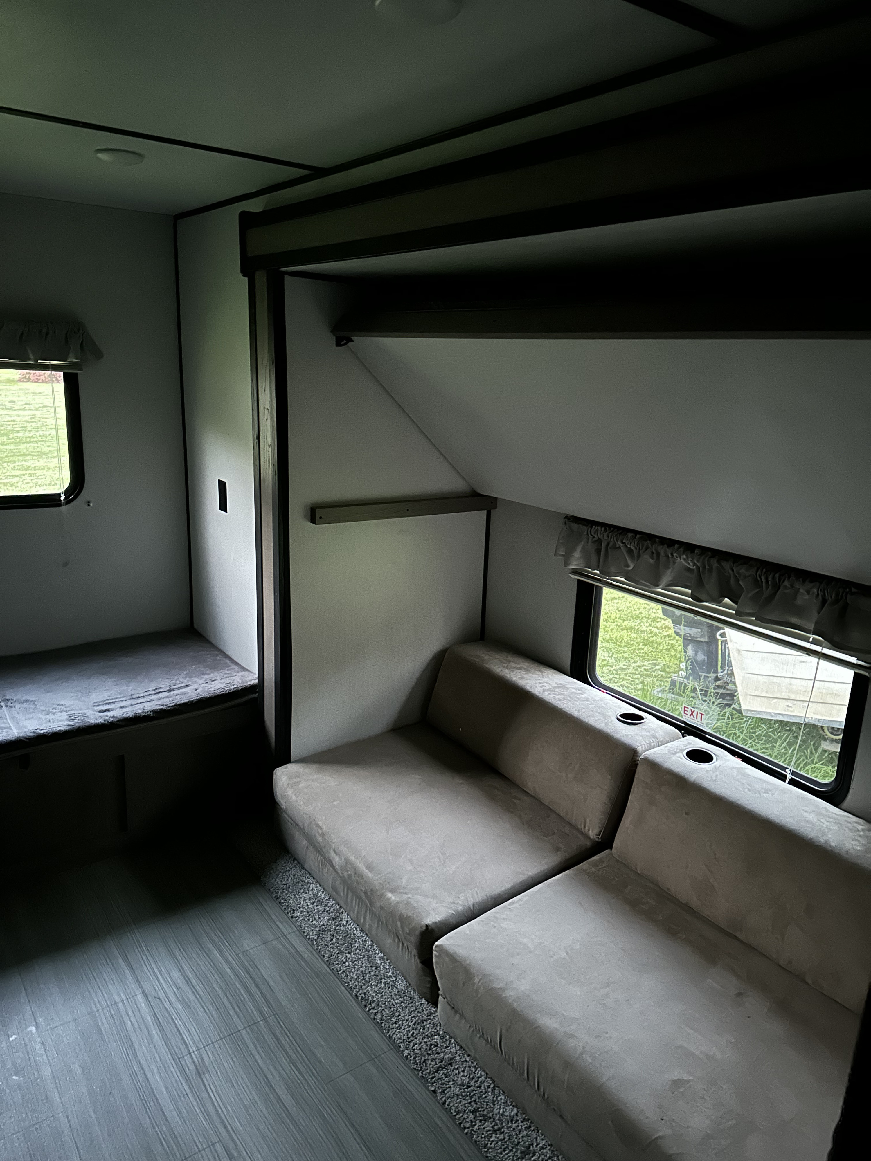 Cozy RV rental interior with bunk, modular sofa with cup holders, and windows showing outdoor greenery. Ideal for trips.. Keystone RV Hideout LHS 2020