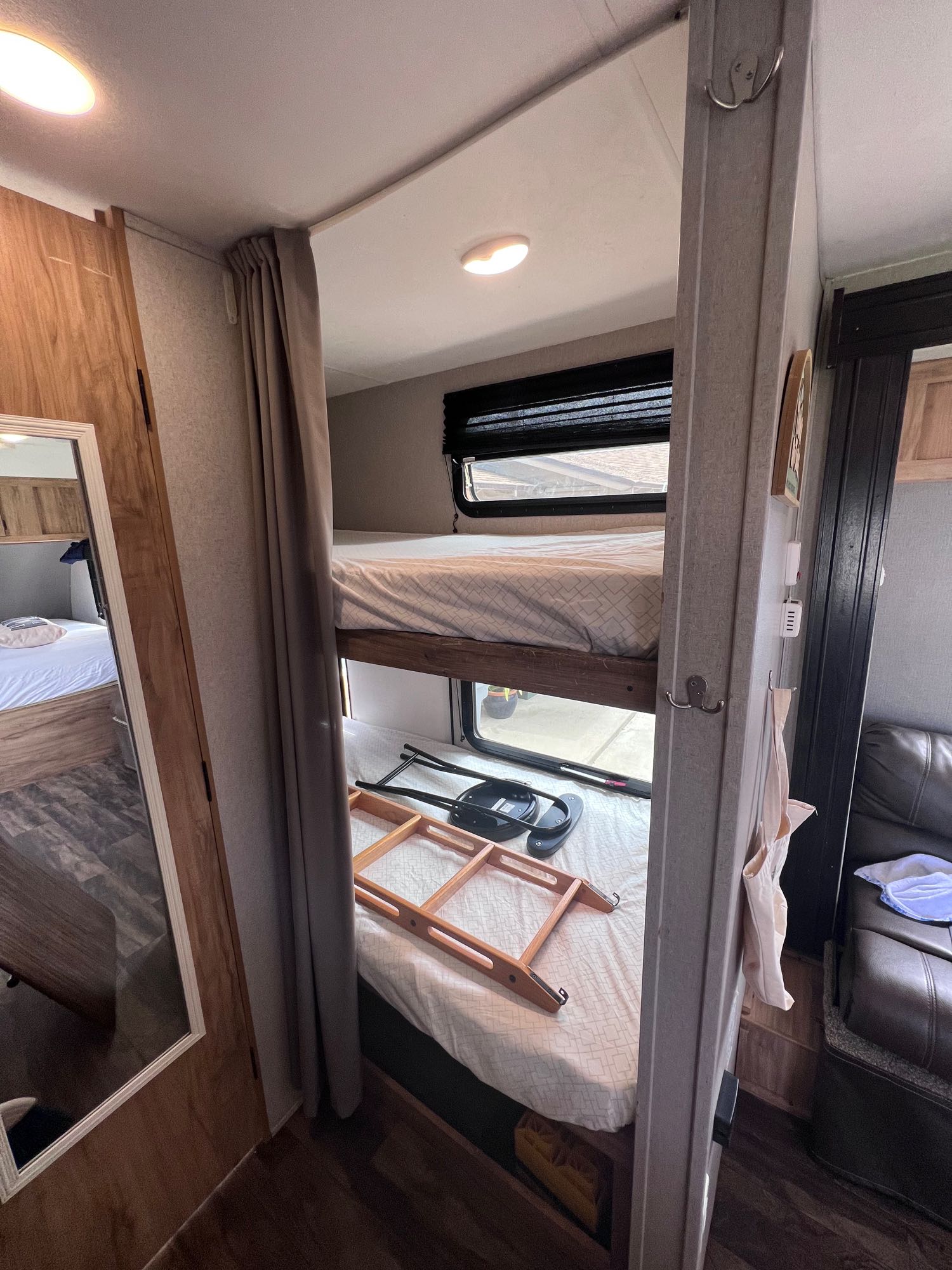 Inside an RV rental: a cozy space with stacked bunk beds, a ladder, privacy curtain, and a full-length mirror.. Coachmen Other 2019