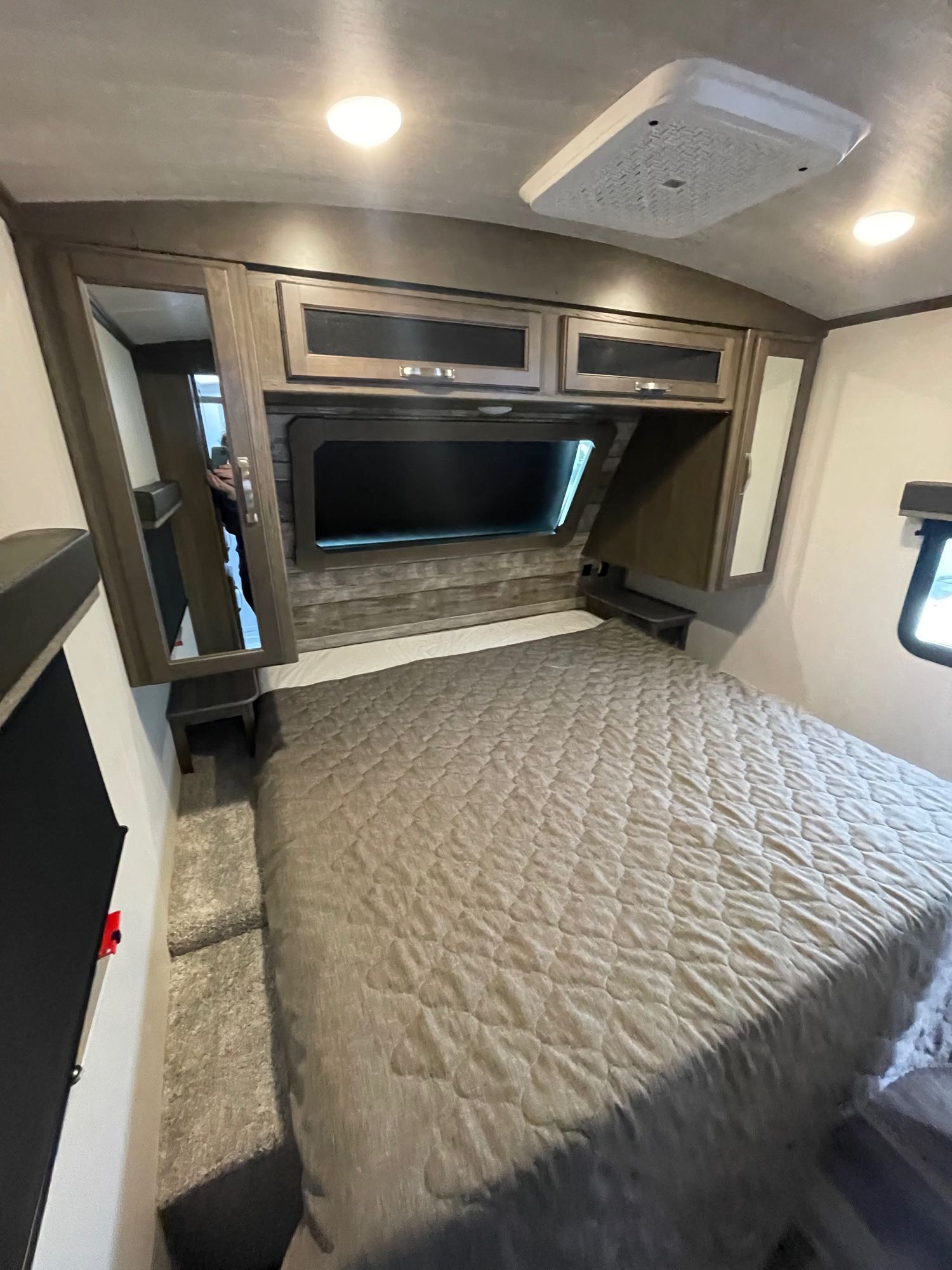 Experience comfort in this rv rental bedroom with a large bed, overhead storage, and a window.. Keystone Cougar 2023