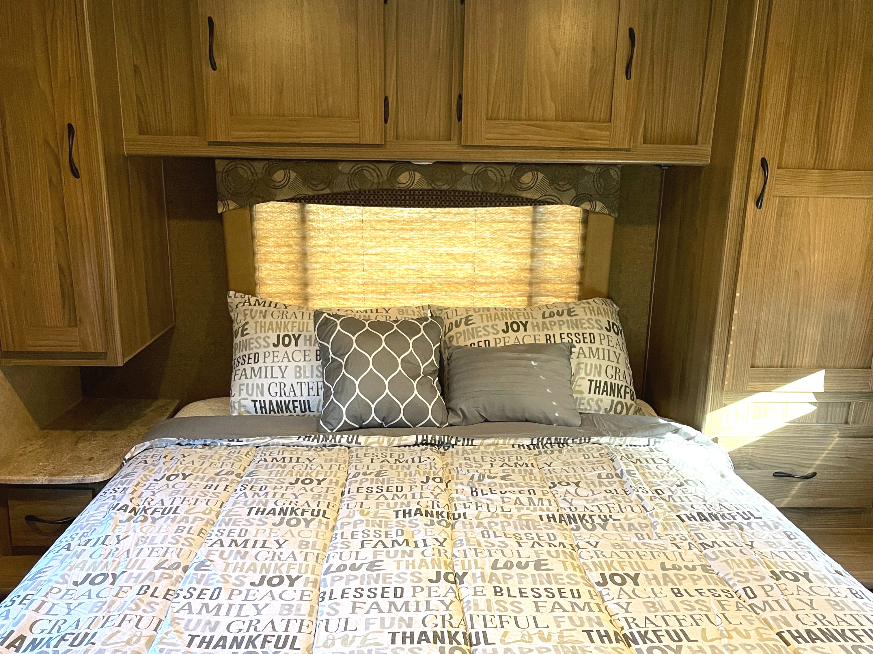 RV rental bedroom: A comfortable bed with inspirational word bedding, surrounded by warm wooden cabinetry.. Other Other 2016